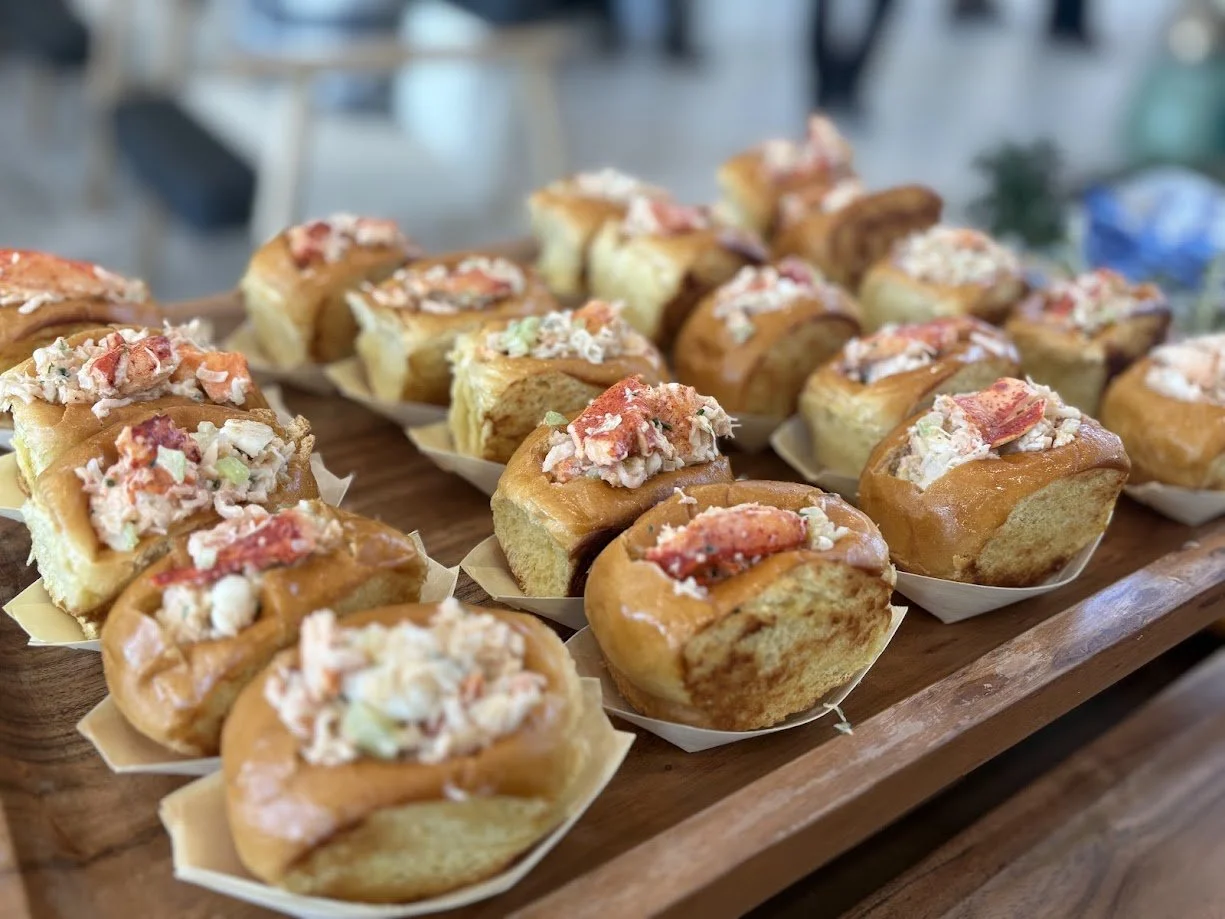 Tray of seafood salad stuffed bread rolls on a wooden serving tray.