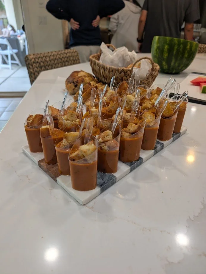 A tray of individual servings of chocolate mousse topped with cookies on a marble surface.
