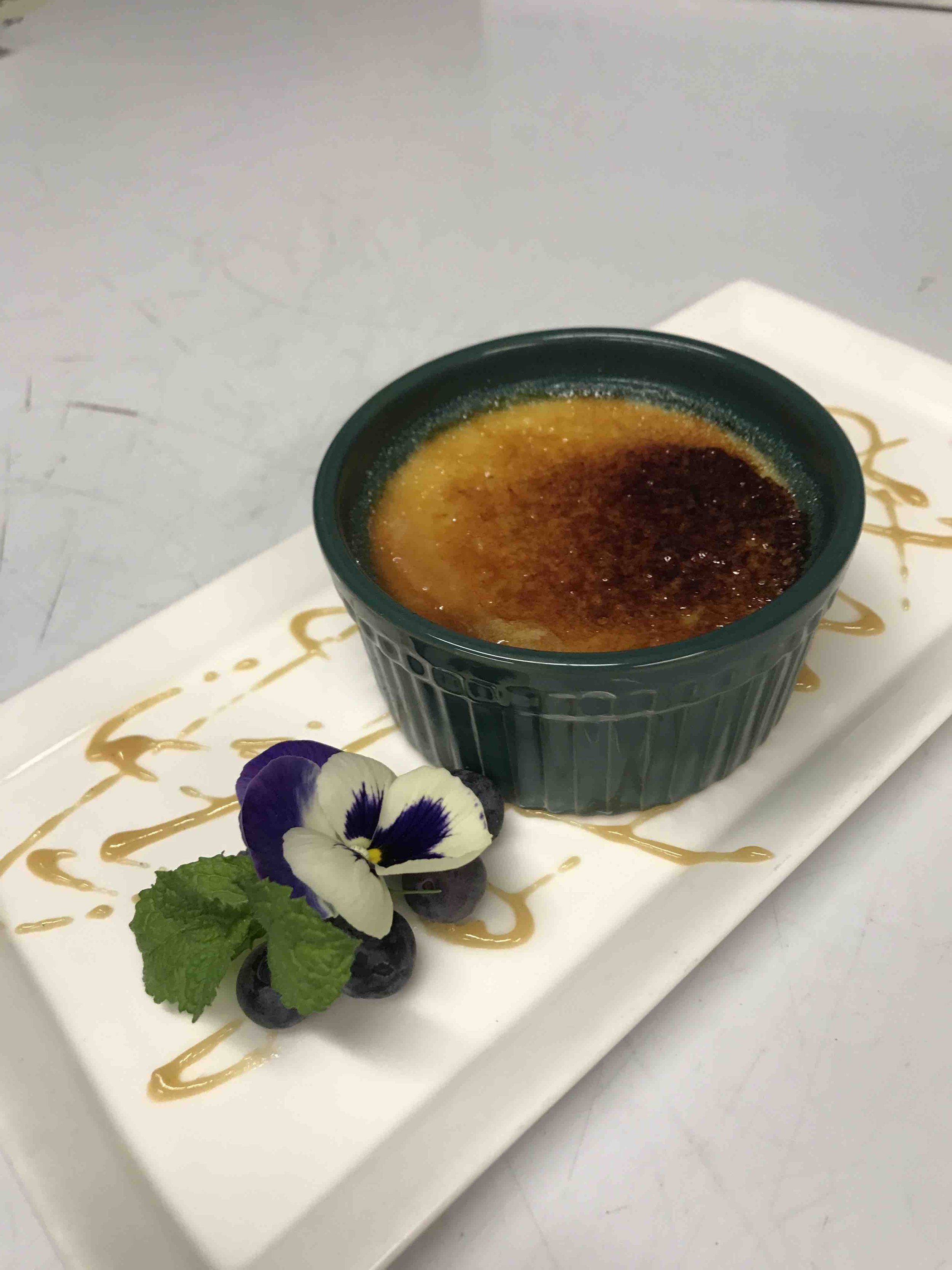 Classic crème brûlée with a caramelized sugar crust, berries and edible flower, part of a luxury dining experience in Utah.