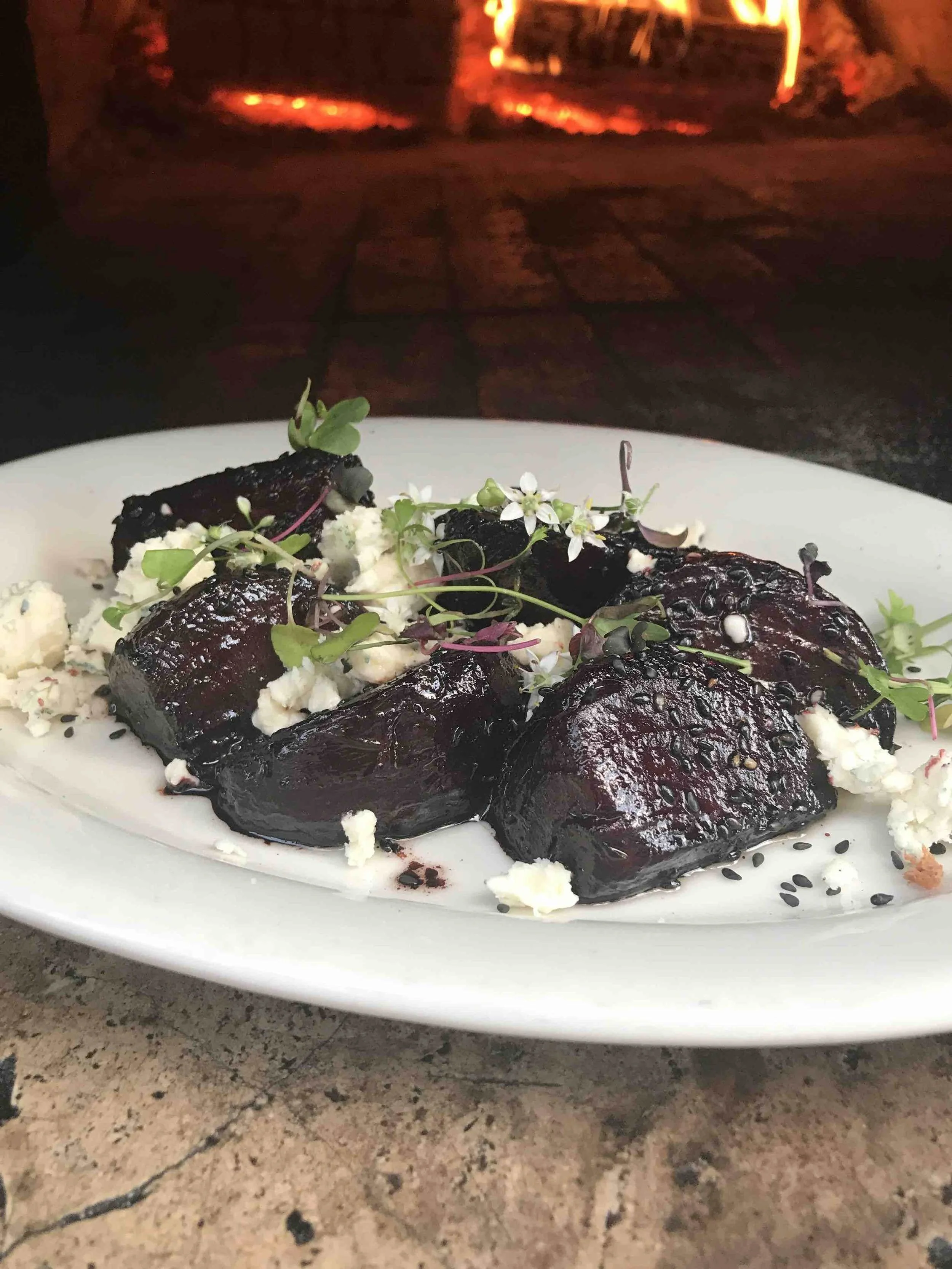 Glazed roasted beets with crumbled cheese, microgreens and edible flowers, beautifully plated as part of luxury private dining.