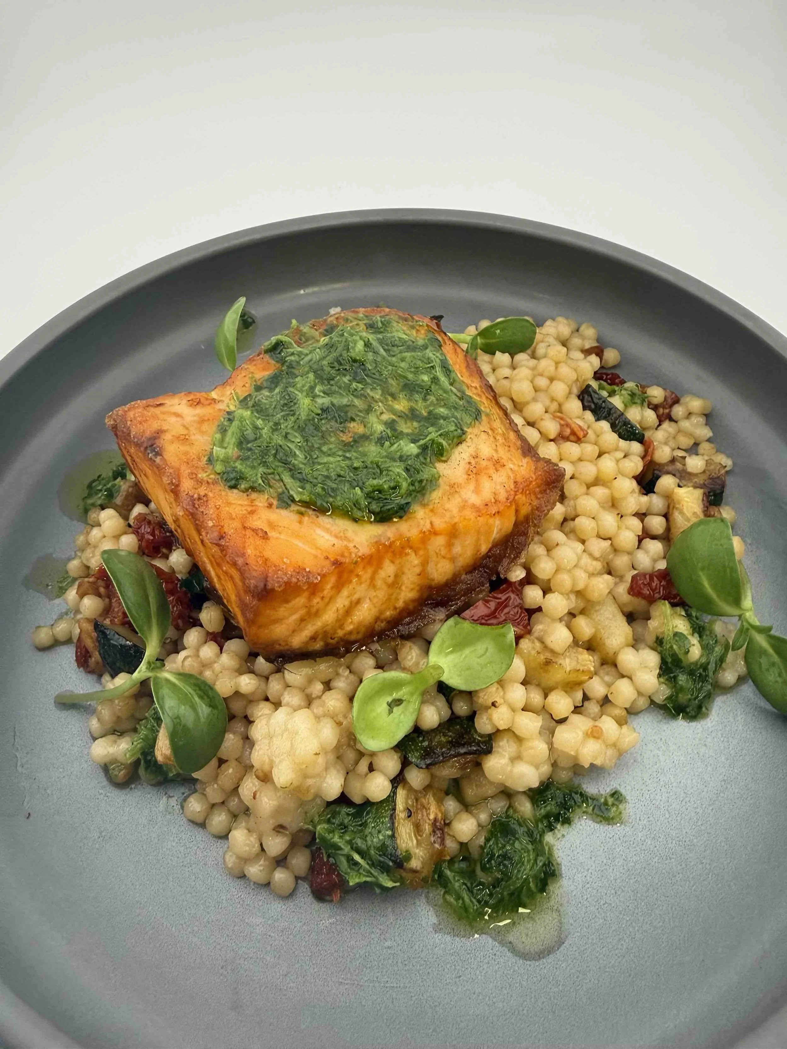 Seared salmon with herb sauce, pearl couscous and vegetables, prepared by a private chef for wedding celebrations as part of catering for wedding and wedding dinner service.