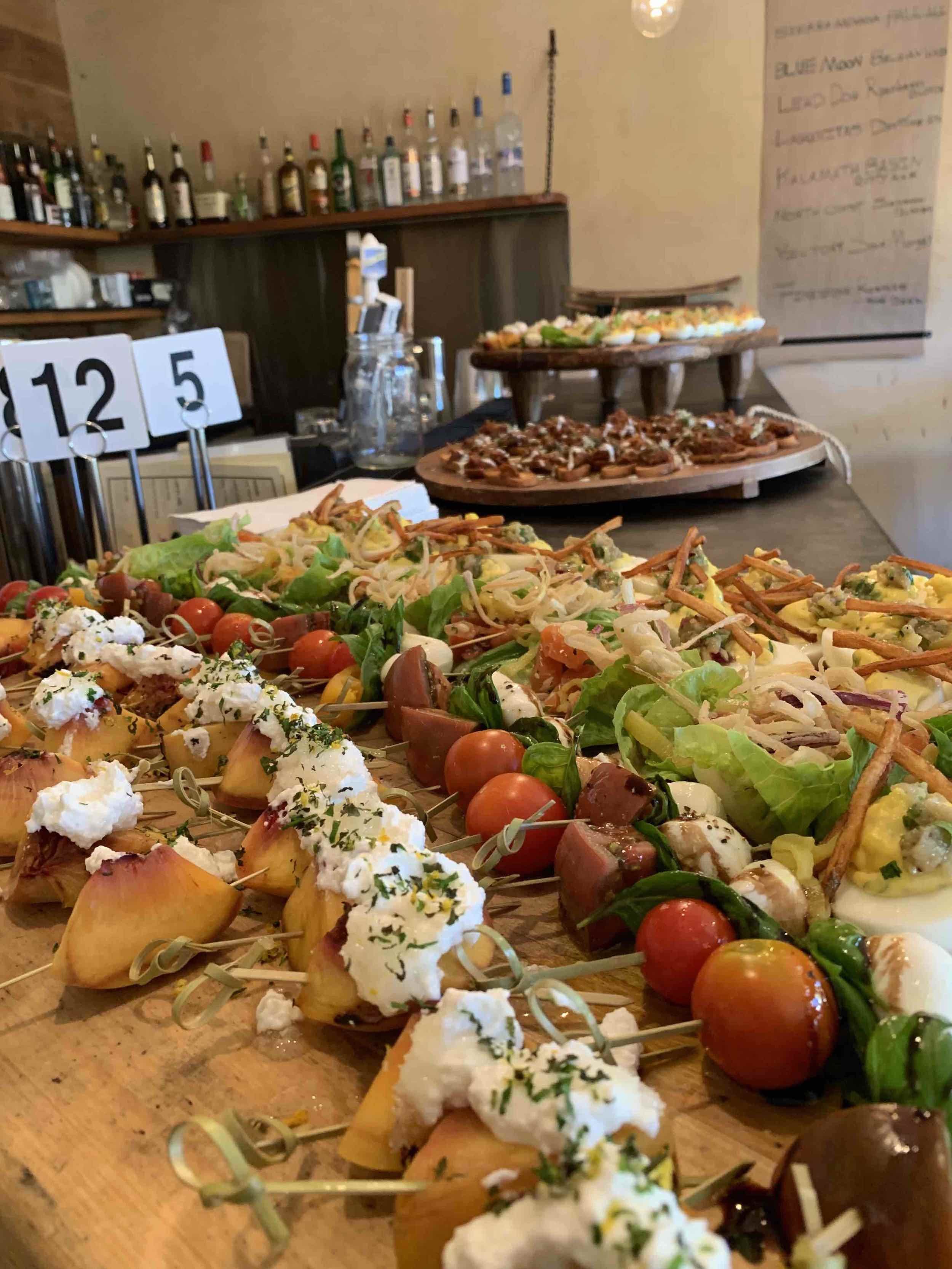 Colorful catered spread with fresh salads, tomatoes, mozzarella, basil and assorted appetizers, showcasing catering Utah, catering services Utah, and private catering services.