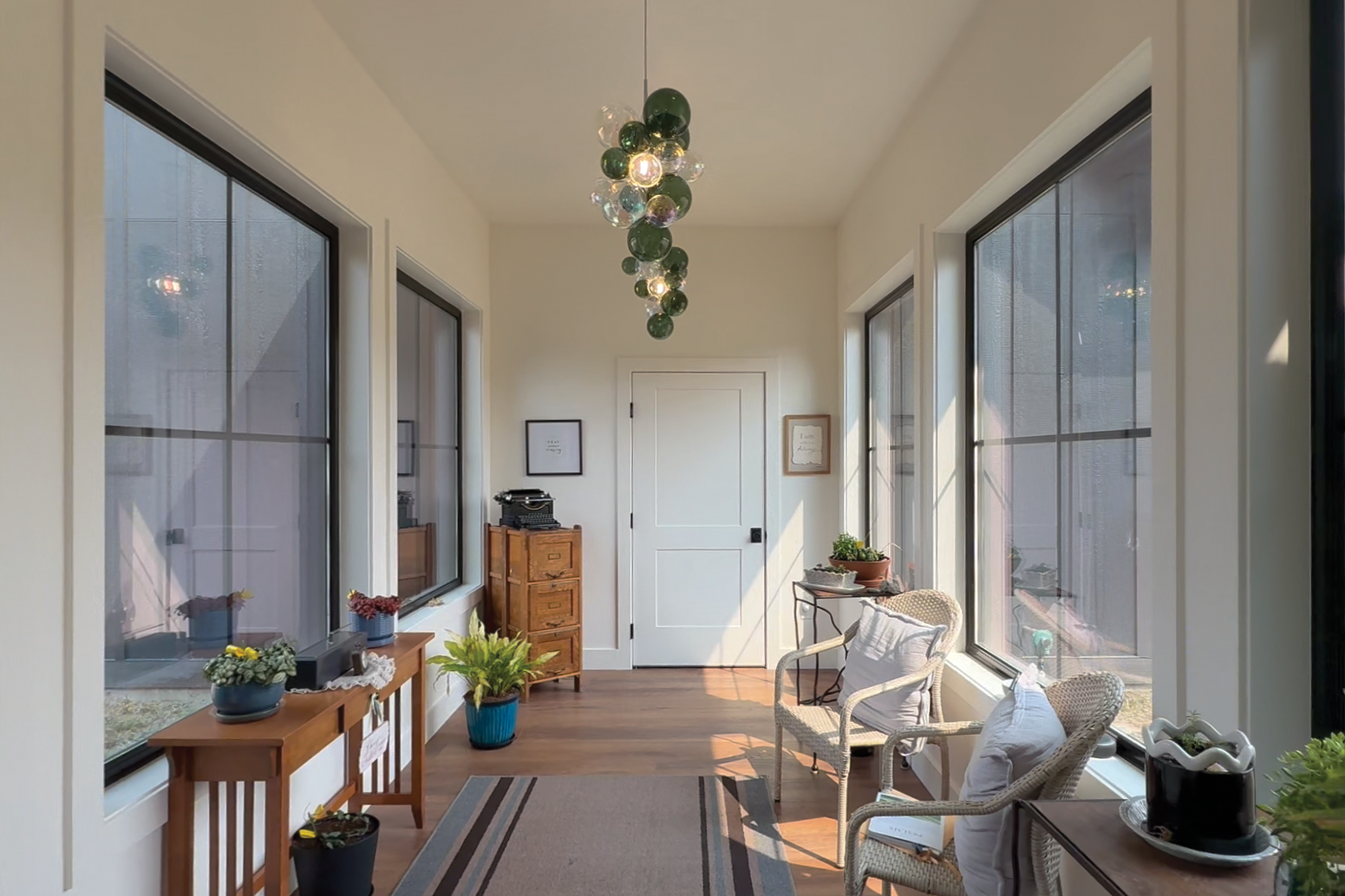 Sunroom featuring large windows, decorated with furniture and houseplants.