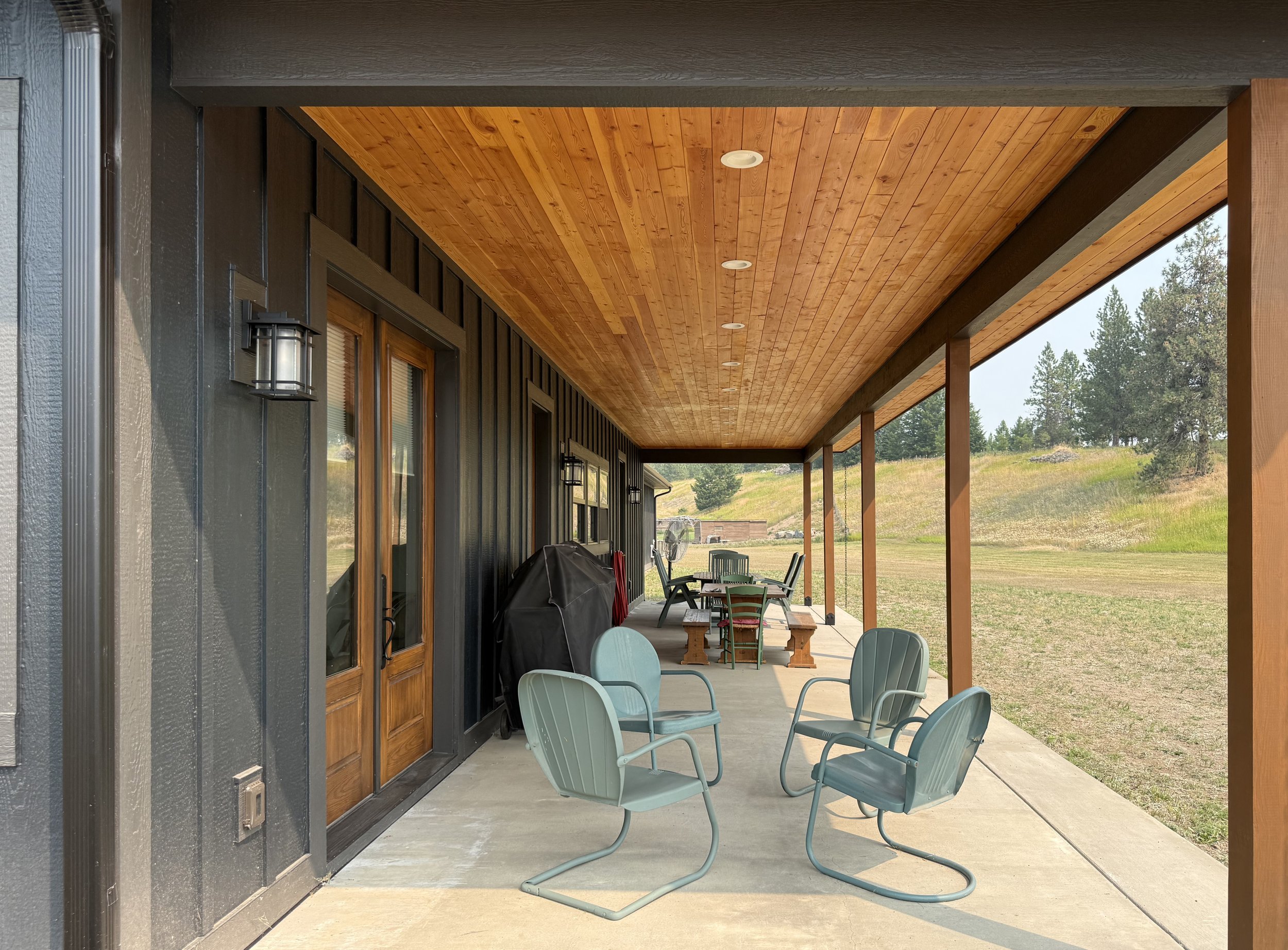 Outdoor porch with featuring wooden accents, with patio furniture, set on a grassy field.