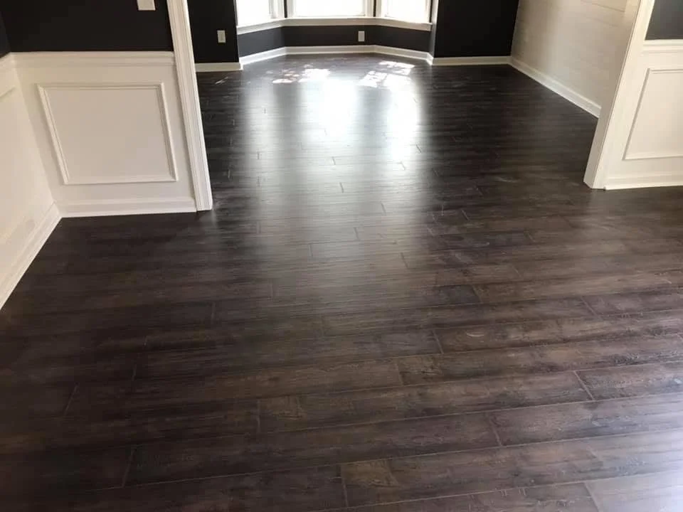 Empty room with dark wood flooring, black and white walls, and a bay window
