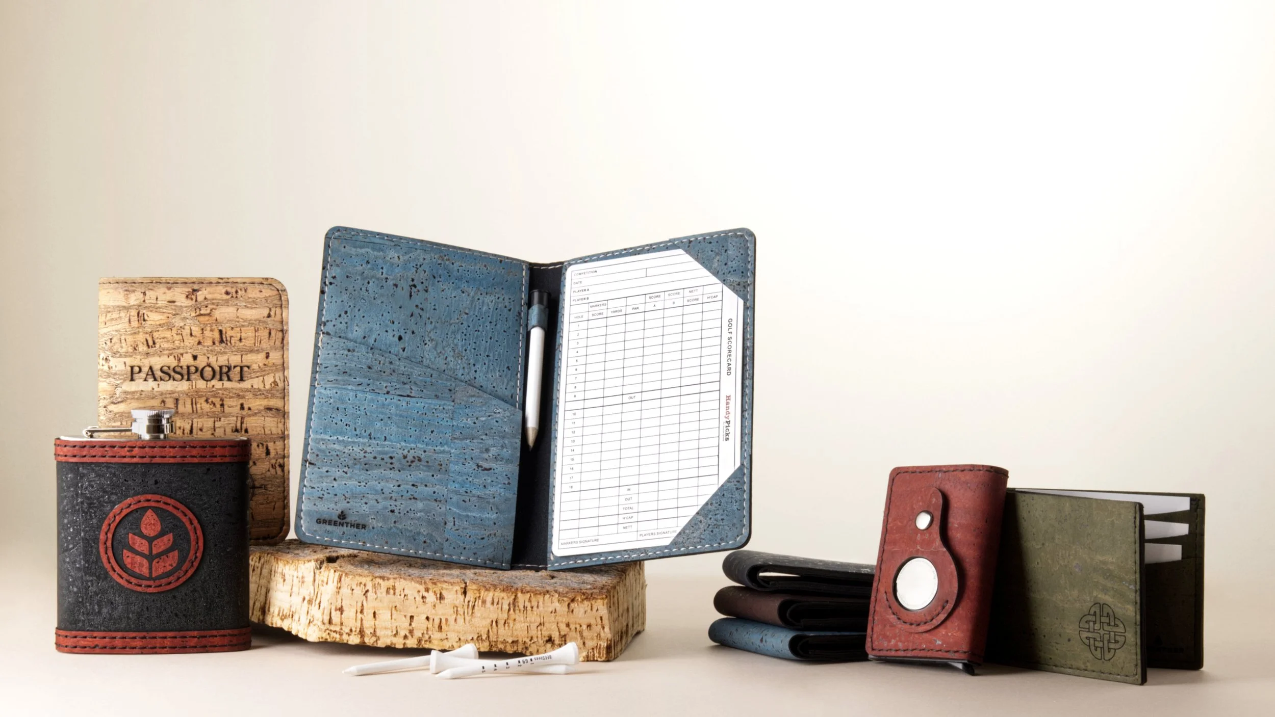 Various travel and golf accessories arranged on a white surface, including a passport holder, a golf scorecard, a leather wallet, and small pouches.