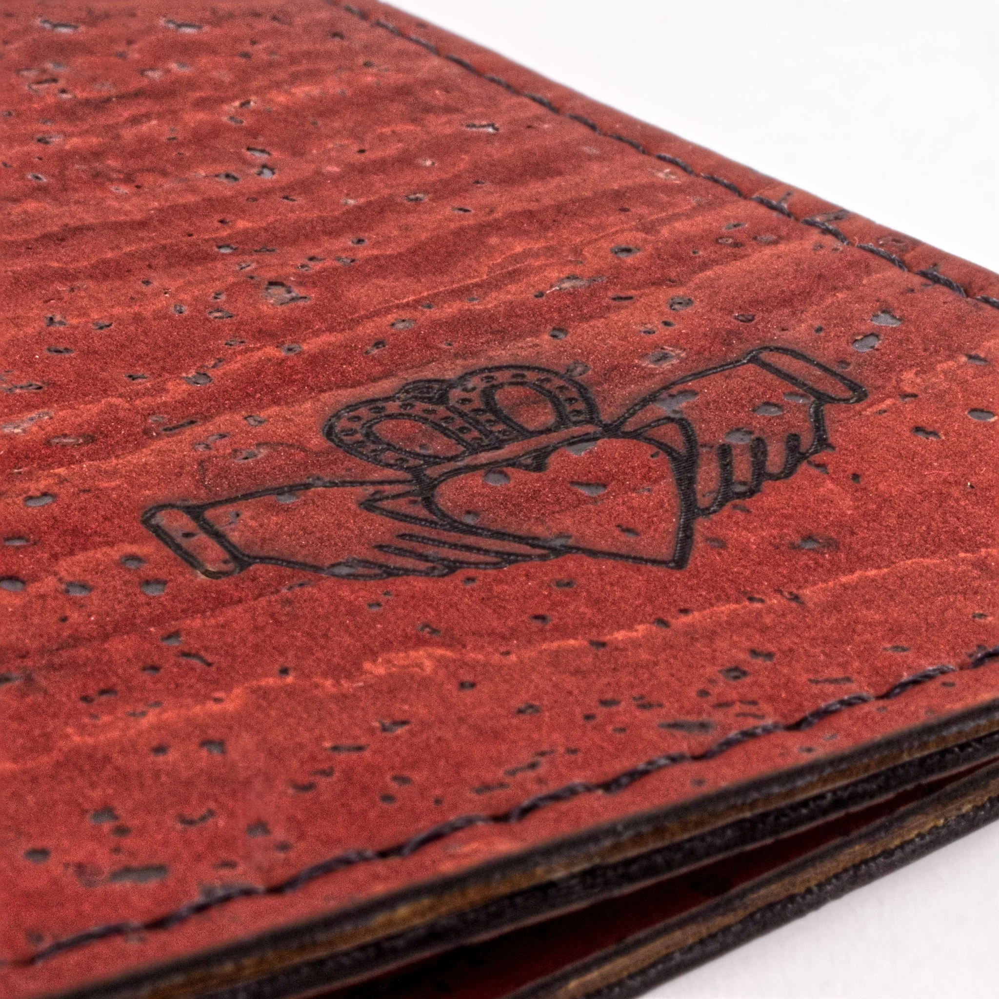 Close-up of a red leather wallet with black stitching and perforated detailing.