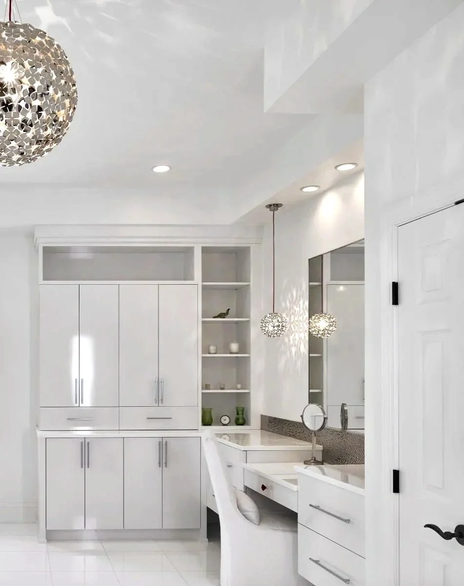 White built-in cabinetry and shelves with decor items, a white desk with a small mirror, and two hanging decorative pendant lights in a bright modern room.