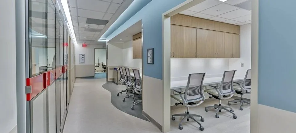 Medical office with a hallway and consultation rooms featuring chairs and cabinetry.