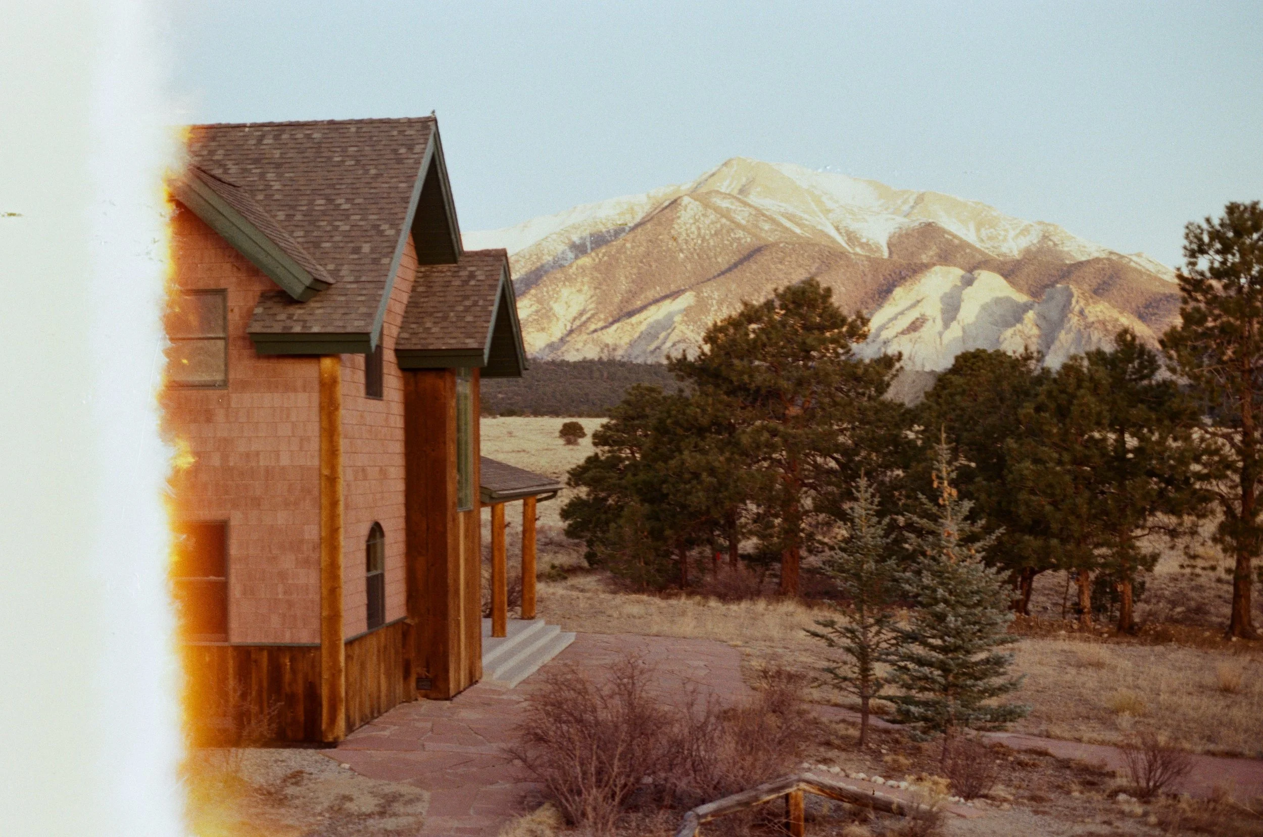 A house under construction with a snow-capped mountain in the background.