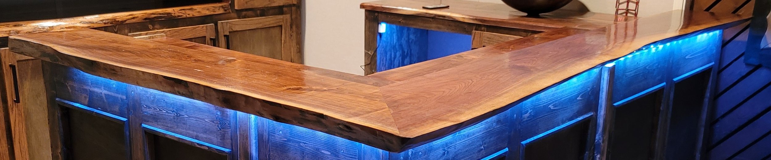 A wooden bar counter with blue LED lighting underneath the countertop.