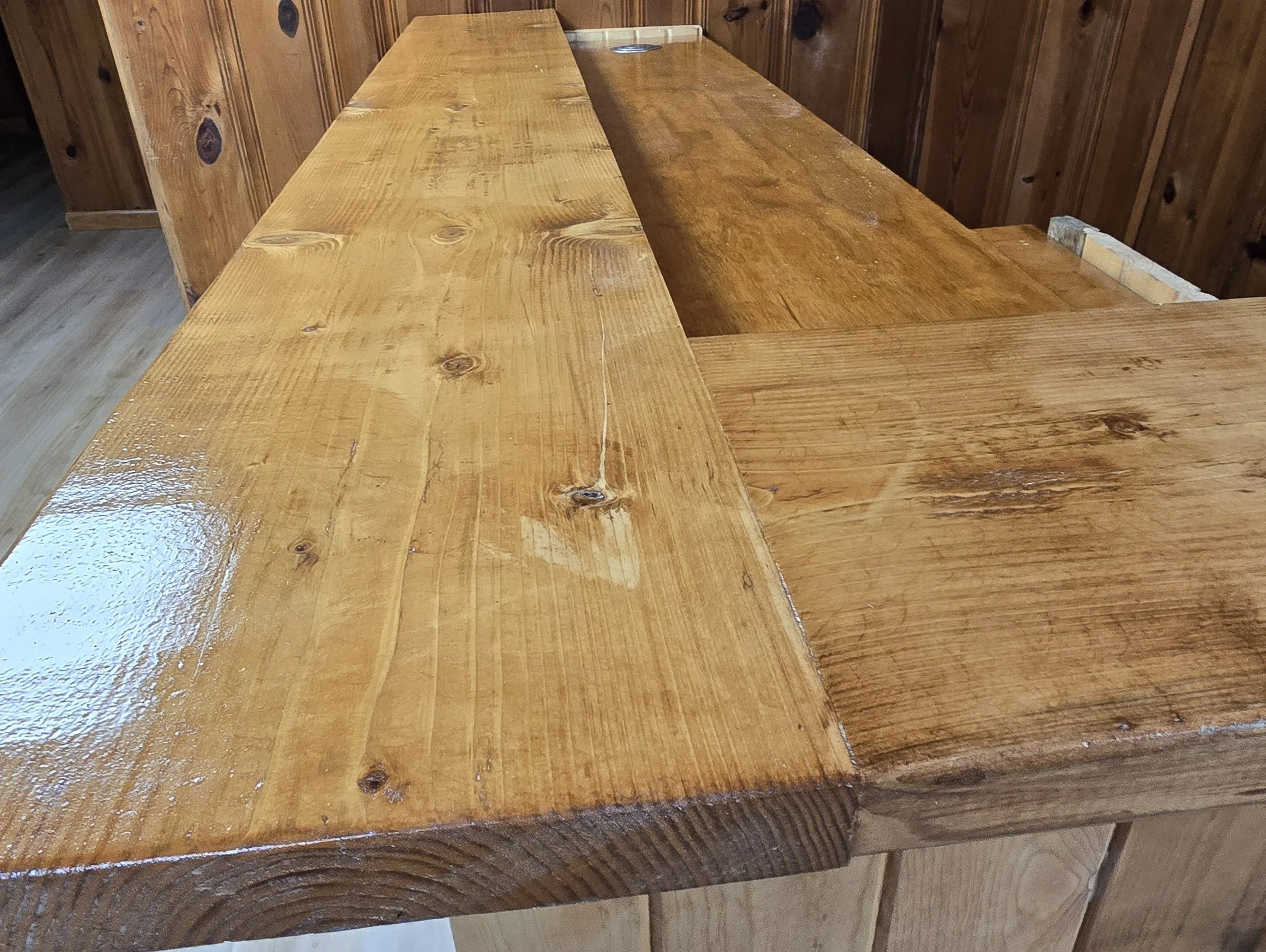 Close-up of a polished wooden table with a wood-paneled wall in the background.