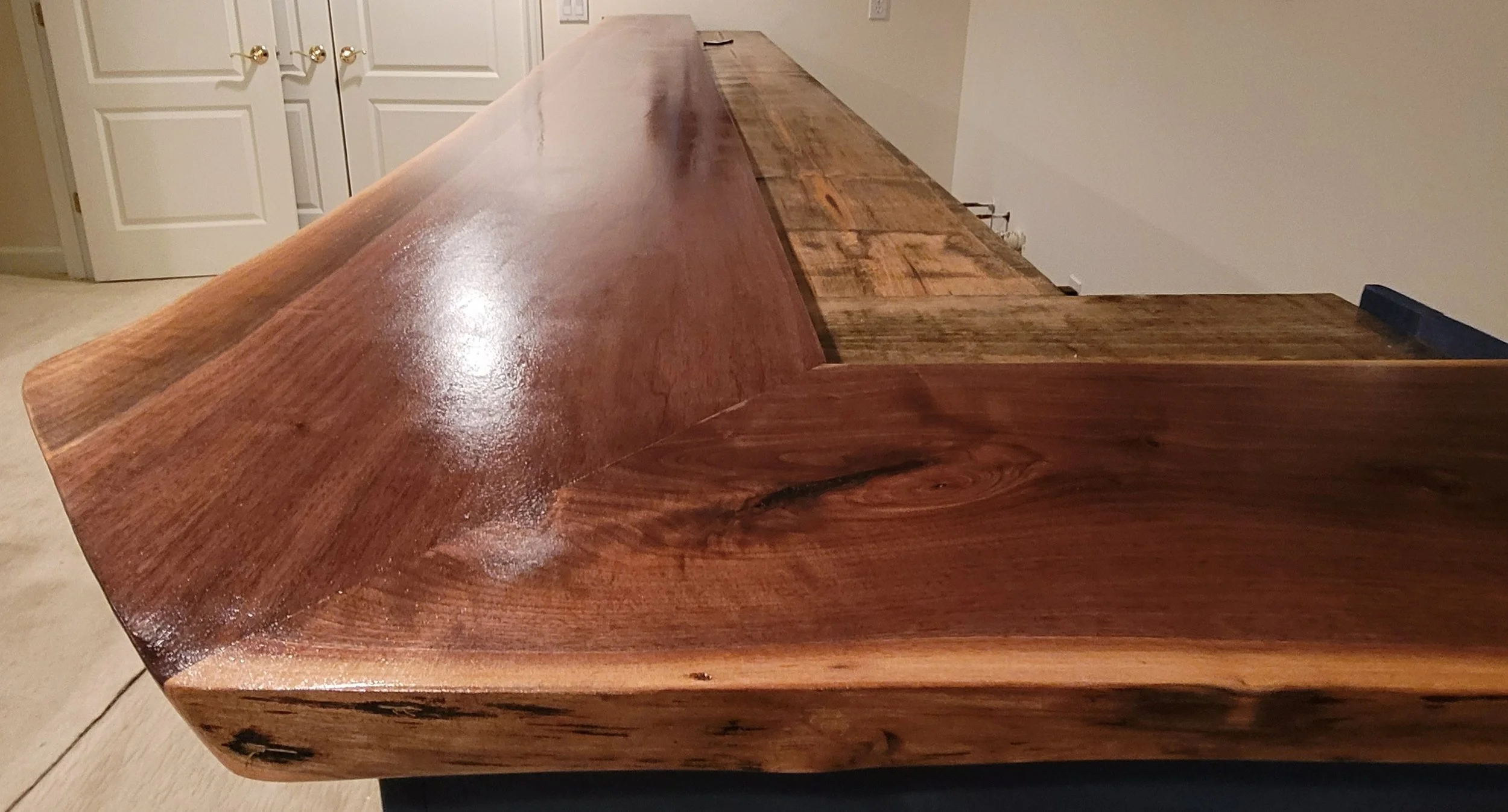 A wooden table with a polished surface and a natural wood finish, positioned in a room with closed white double doors in the background.