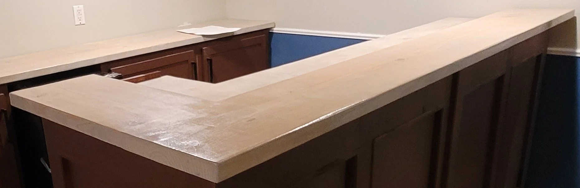 The image shows a wooden countertop or bar top that is being installed or constructed, with the underside still visible.