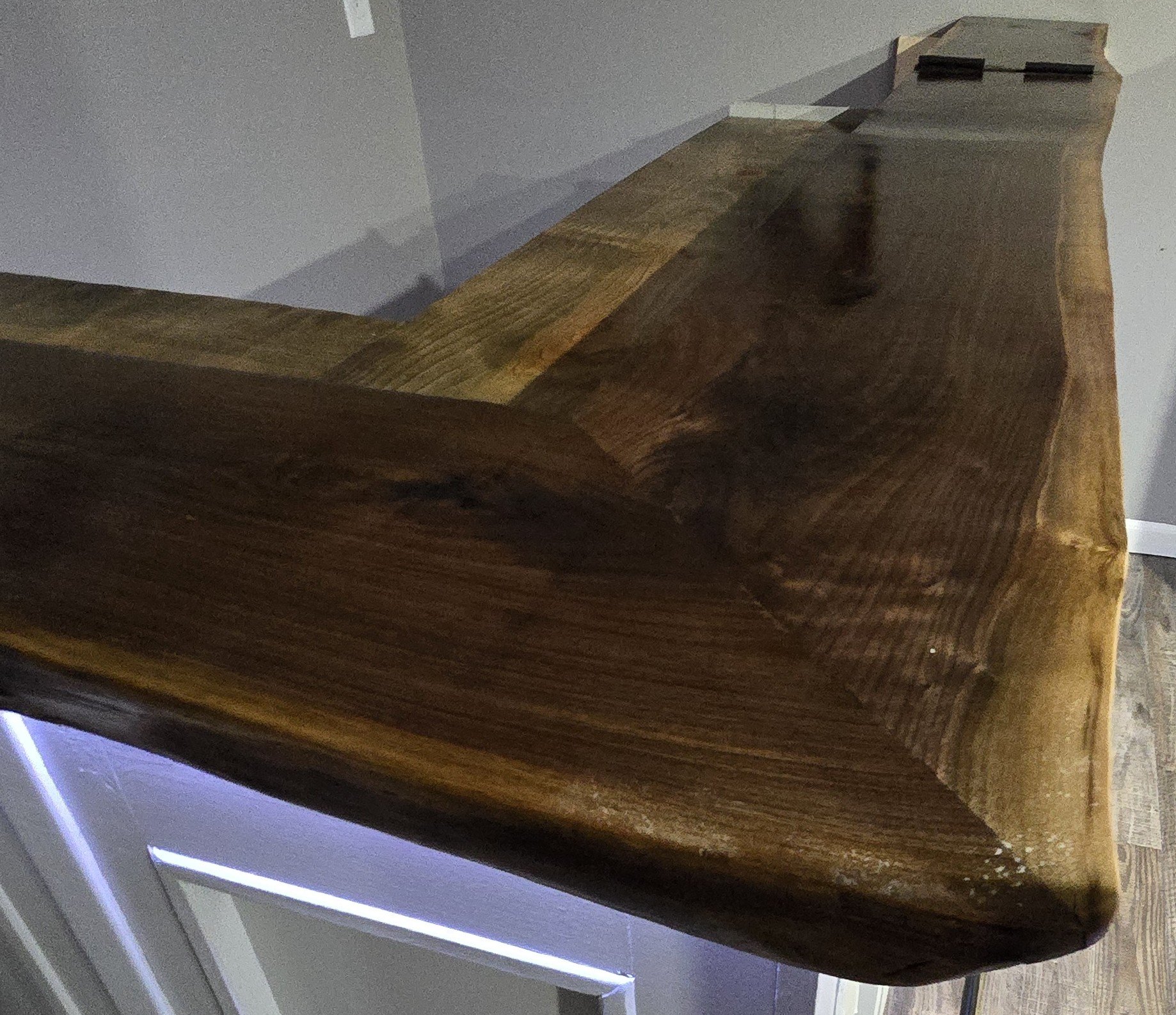 Close-up of a wooden countertop with a piece of black marker on the top edge, and a white wall in the background.