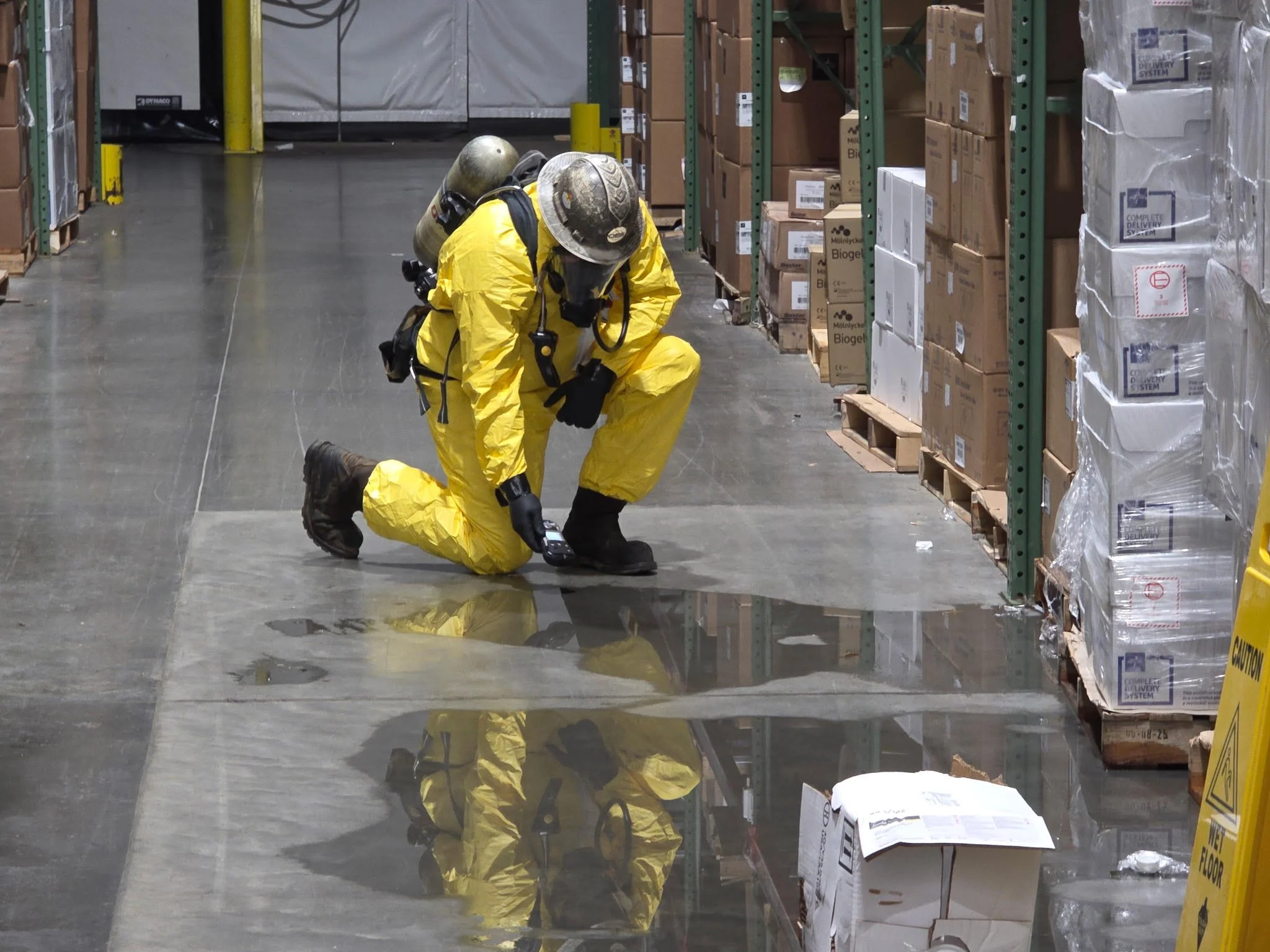 Hazmat technician in protective equipment performing environmental cleanup inside an industrial facility.