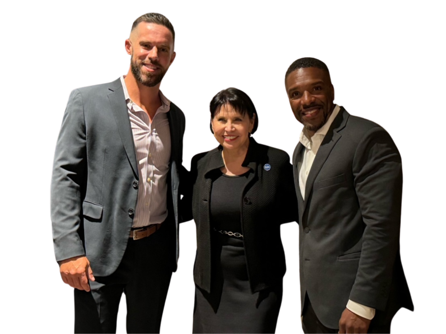Three professionally dressed individuals standing together, smiling, against a plain background. Two men are wearing suits, and a woman is in a blazer.