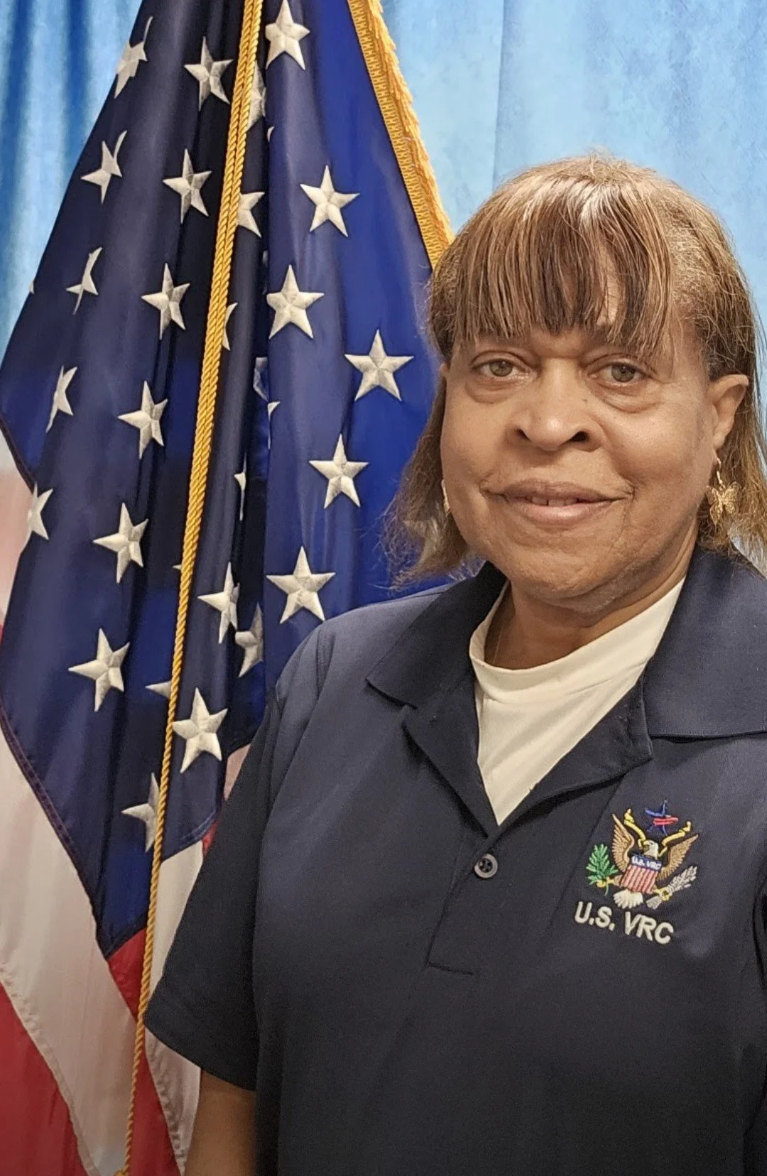 A woman in a U.S. VRC uniform standing in front of an American flag.