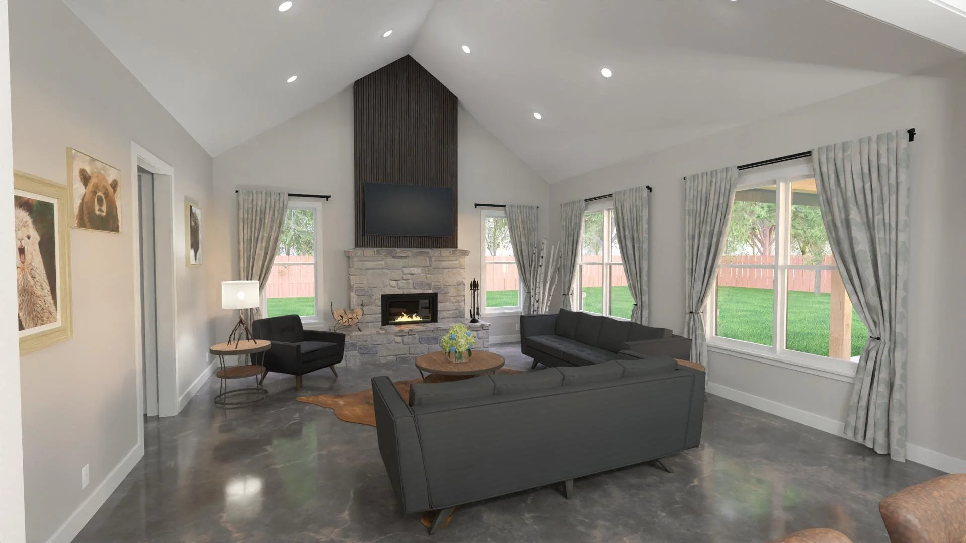Living room with gray sofas, a stone fireplace with a television mounted above it, large windows with curtains, and artwork of bears on the wall. There are green trees outside and the room has polished gray flooring.