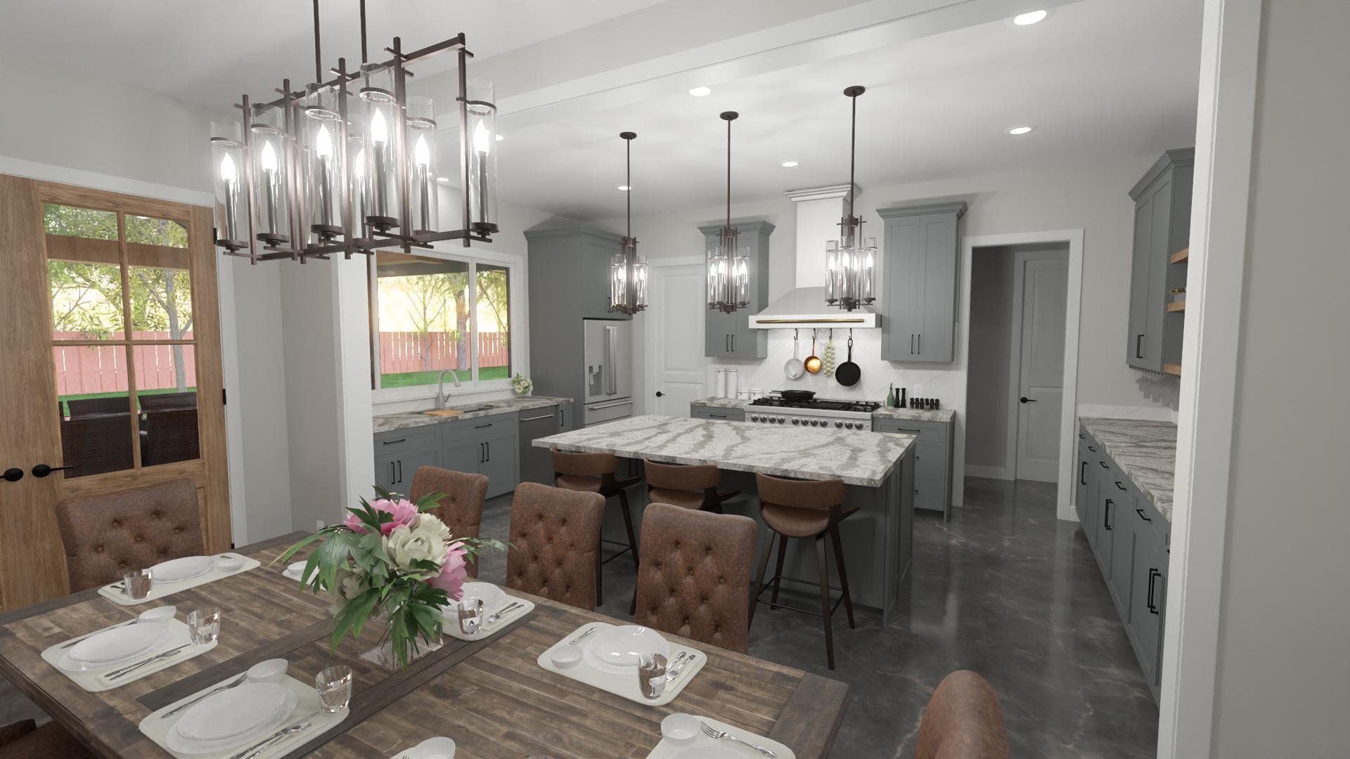 Modern kitchen with gray cabinets, marble island, and industrial-style pendant lighting above the island. A dining table with a floral centerpiece and place settings is in the foreground, with sliding glass door leading to a backyard with a wooden fence and trees.