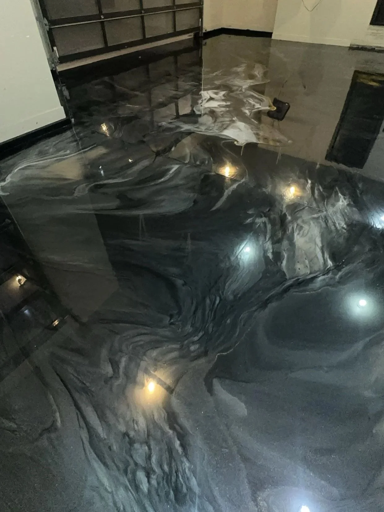A marble floor with black, gray, and white swirling patterns, reflecting lights from above.
