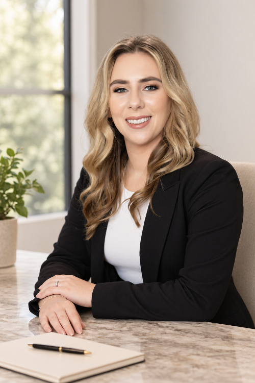 Dr. Jessica Roos in black blazer smiling at a desk with a notebook and pen