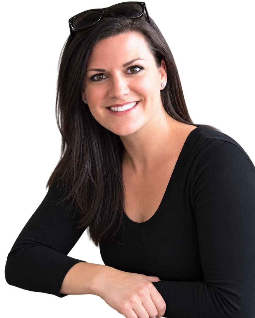 A woman with long dark hair, smiling, wearing a black long-sleeve shirt and sunglasses on her head, sitting with her arm on a surface, facing forward.