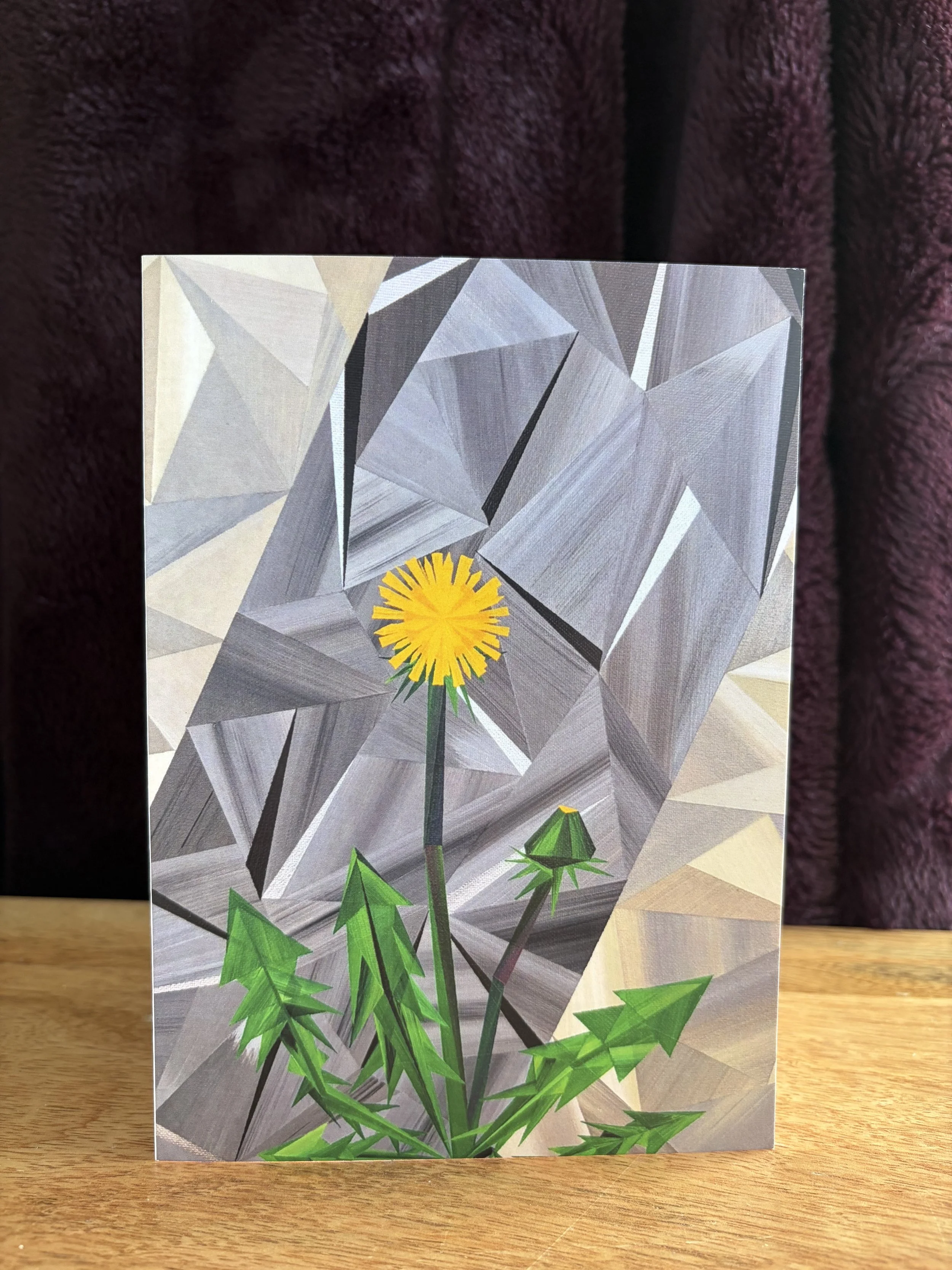 The Lioness greeting card, featuring Marilyn Calleja’s geometric dandelion painting in yellow, green and blue hand-painted triangles.