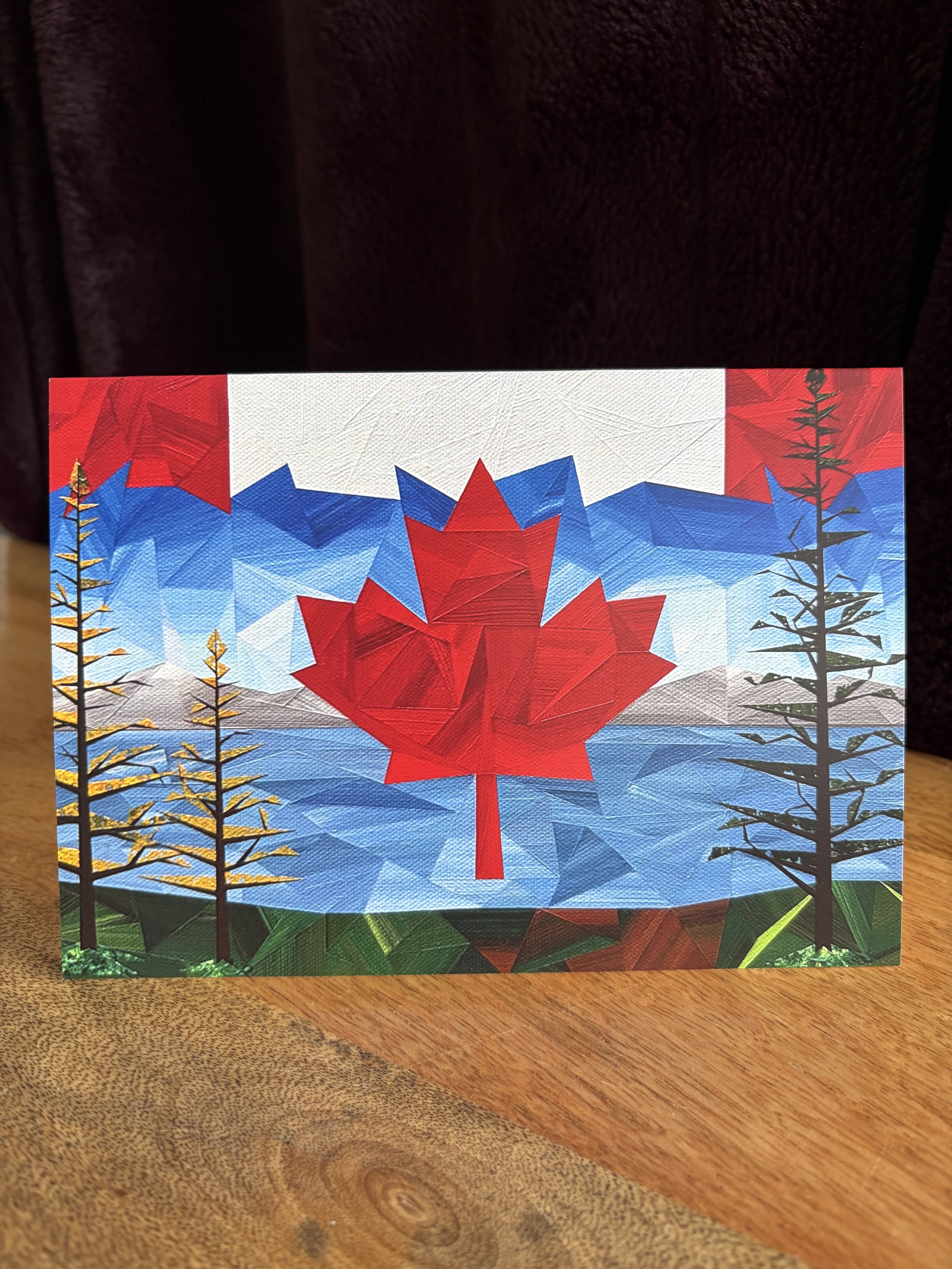 Rooted in the North greeting card, featuring Marilyn Calleja’s geometric forest landscape in layered shades of green and blue.