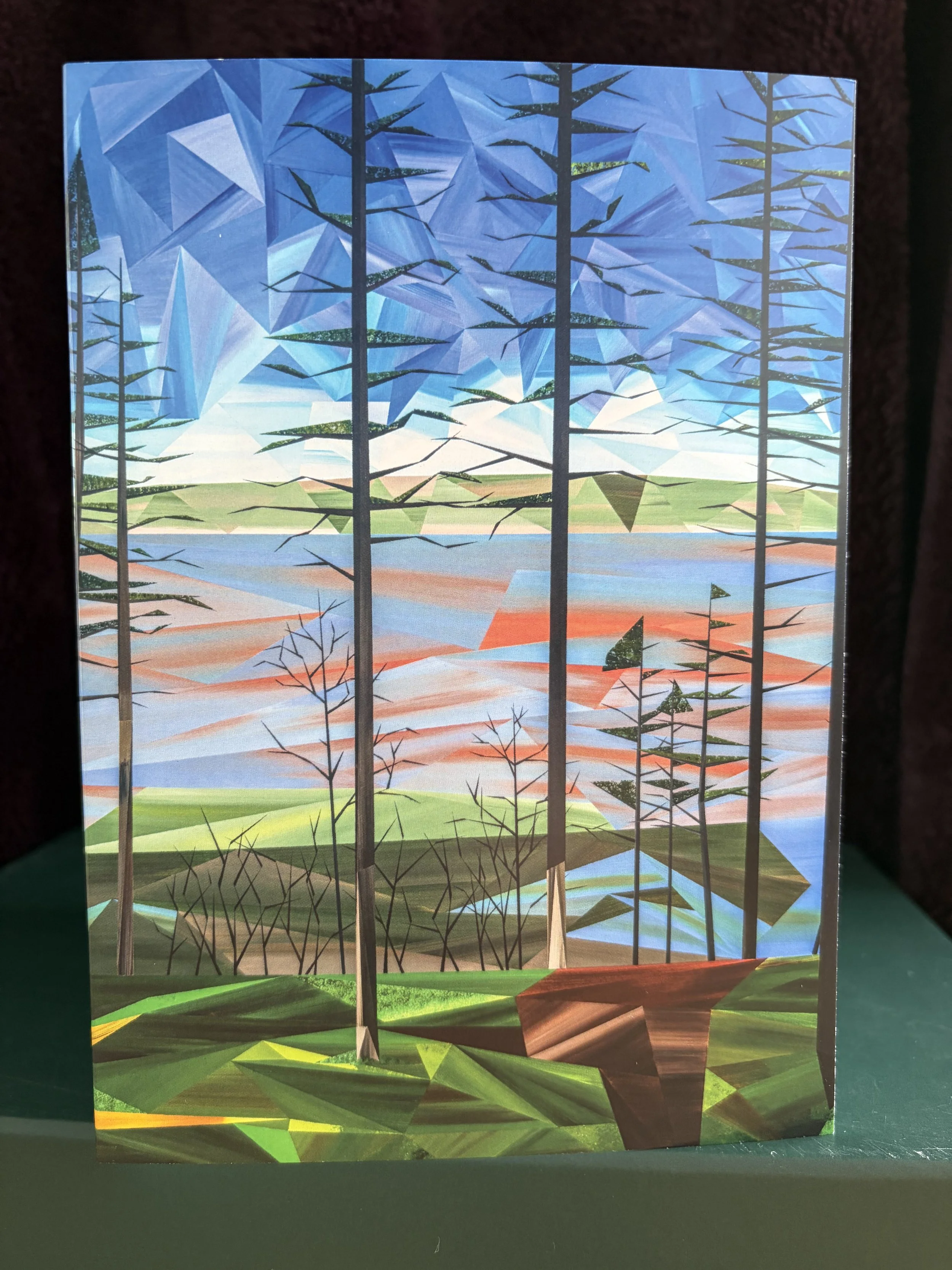 Along the Trail greeting card, featuring Marilyn Calleja’s landscape of tall trees overlooking water beneath a blue sky of hand-painted triangles.