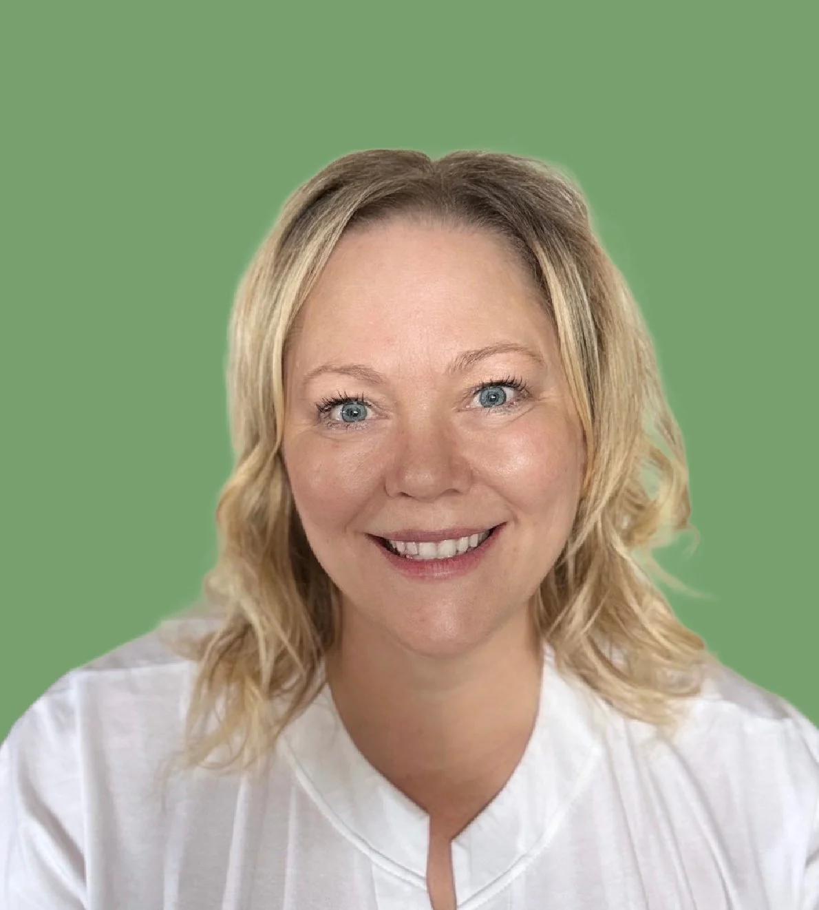 A woman with blonde wavy hair and blue eyes smiling, wearing a white top, against a green background.