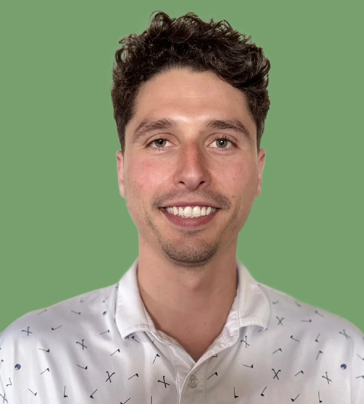 A portrait of a smiling young man with curly brown hair, wearing a white button-up shirt with a small pattern, against a green background.