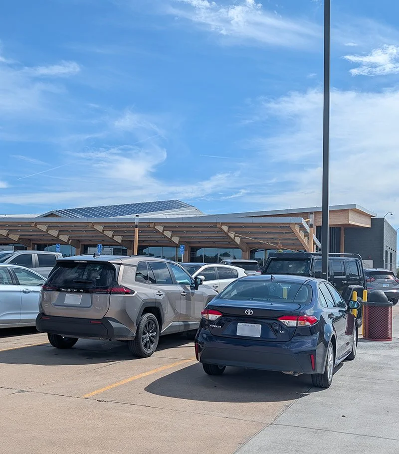 Motor vehicles are seen parked in the lot near the airport's terminal.
