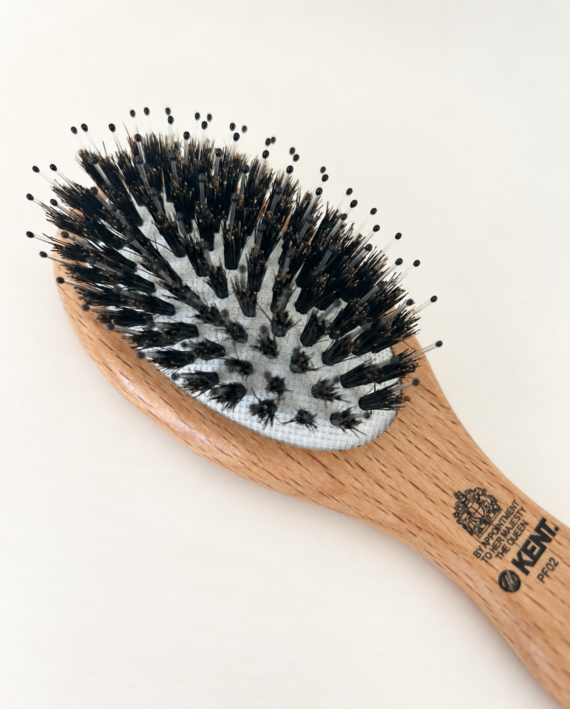 Close-up of a wooden hairbrush with black-tip plastic bristles on a white background.