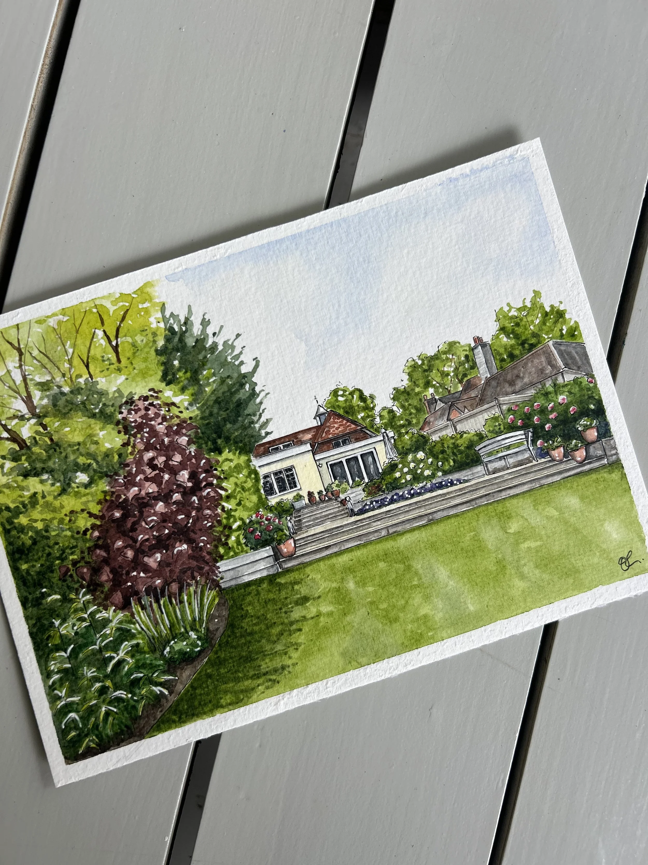 Watercolor painting of a backyard garden with trees, a house, potted plants, and a patio area, on a gray surface.