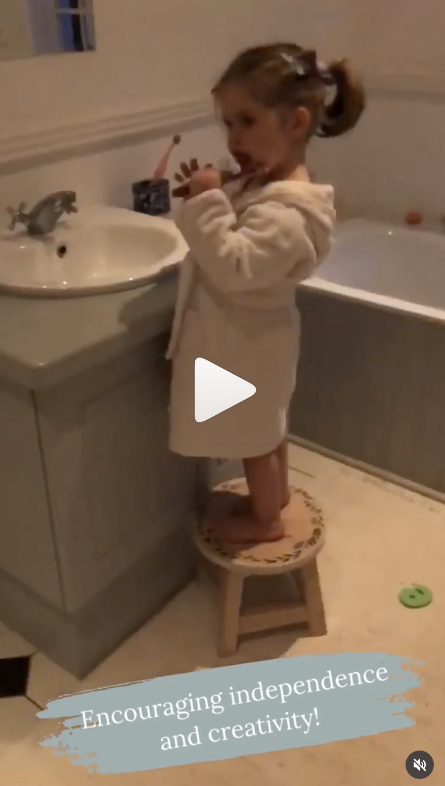 Young girl standing on a small stool brushing her teeth in a bathroom.