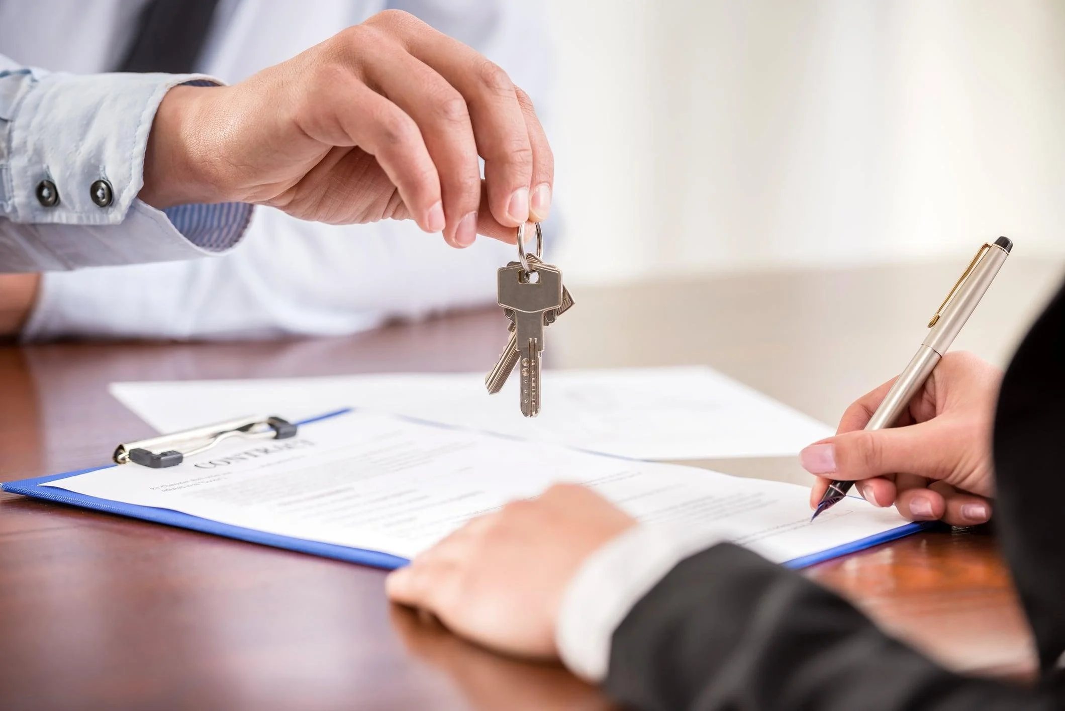 Title professional presents keys during a real estate closing.