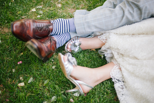 Bride and groom relaxing on the grass in wedding attire, with silver bridal shoes and striped socks, in Healdsburg, California.