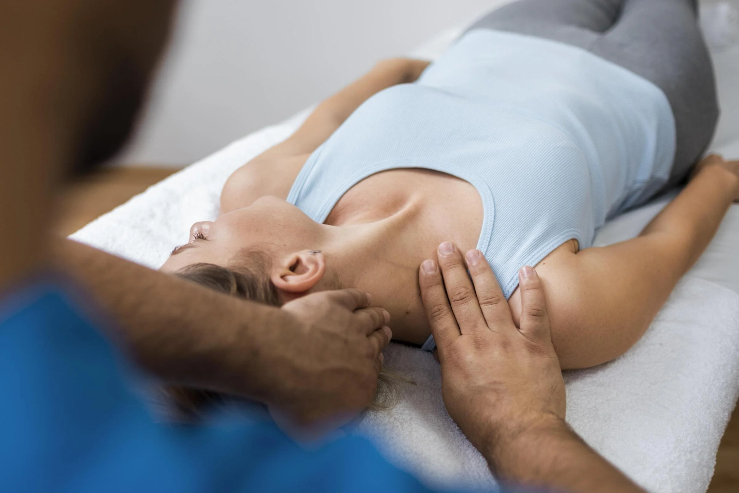 A person lying down, receiving an adjustment or neck therapy from an osteopathic physician.