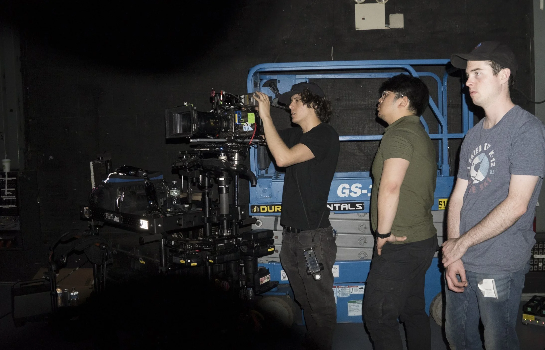Three men on a film set operating a professional camera.