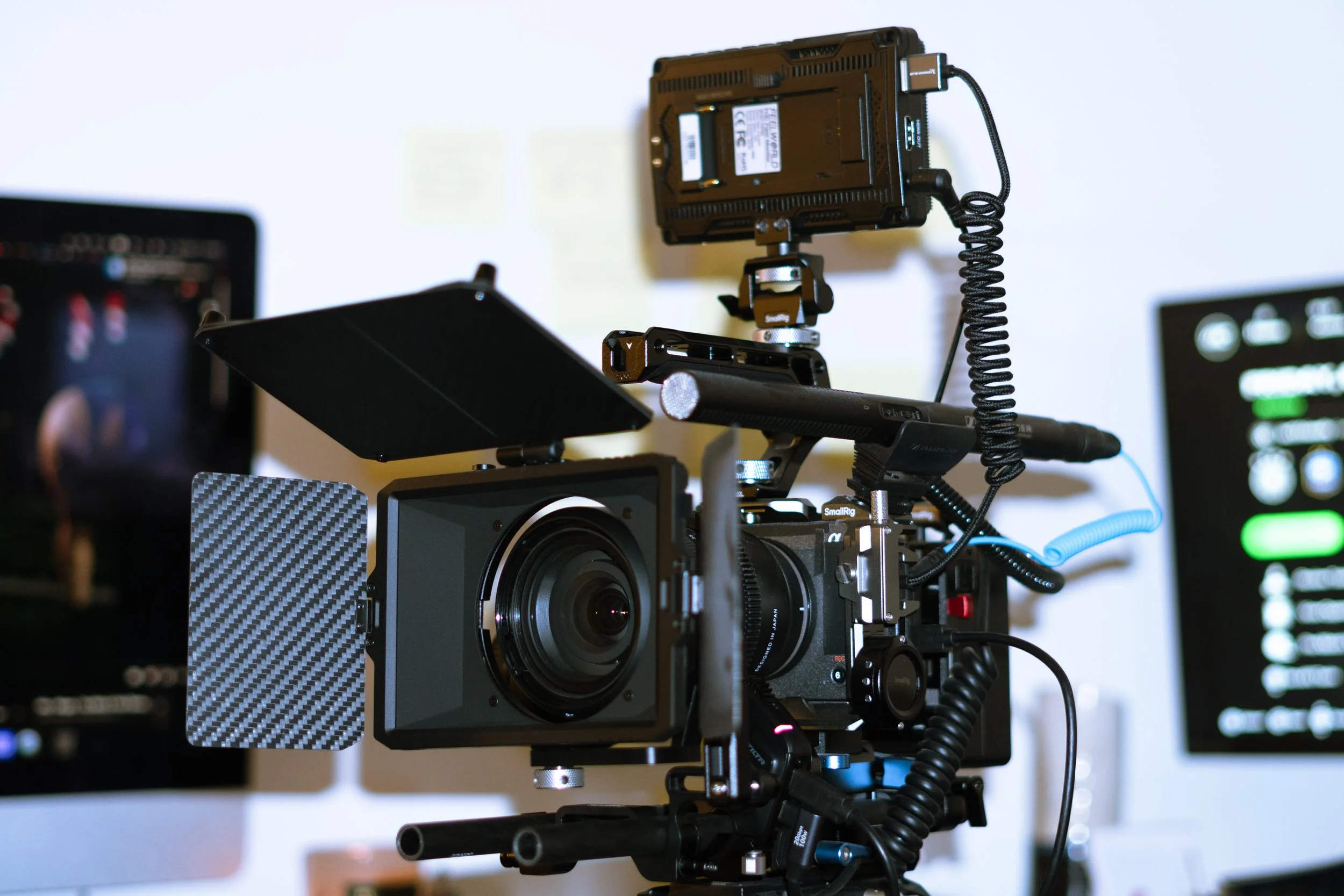 Professional camera mounted on a rig with various accessories, including a monitor and lights, on a desk.