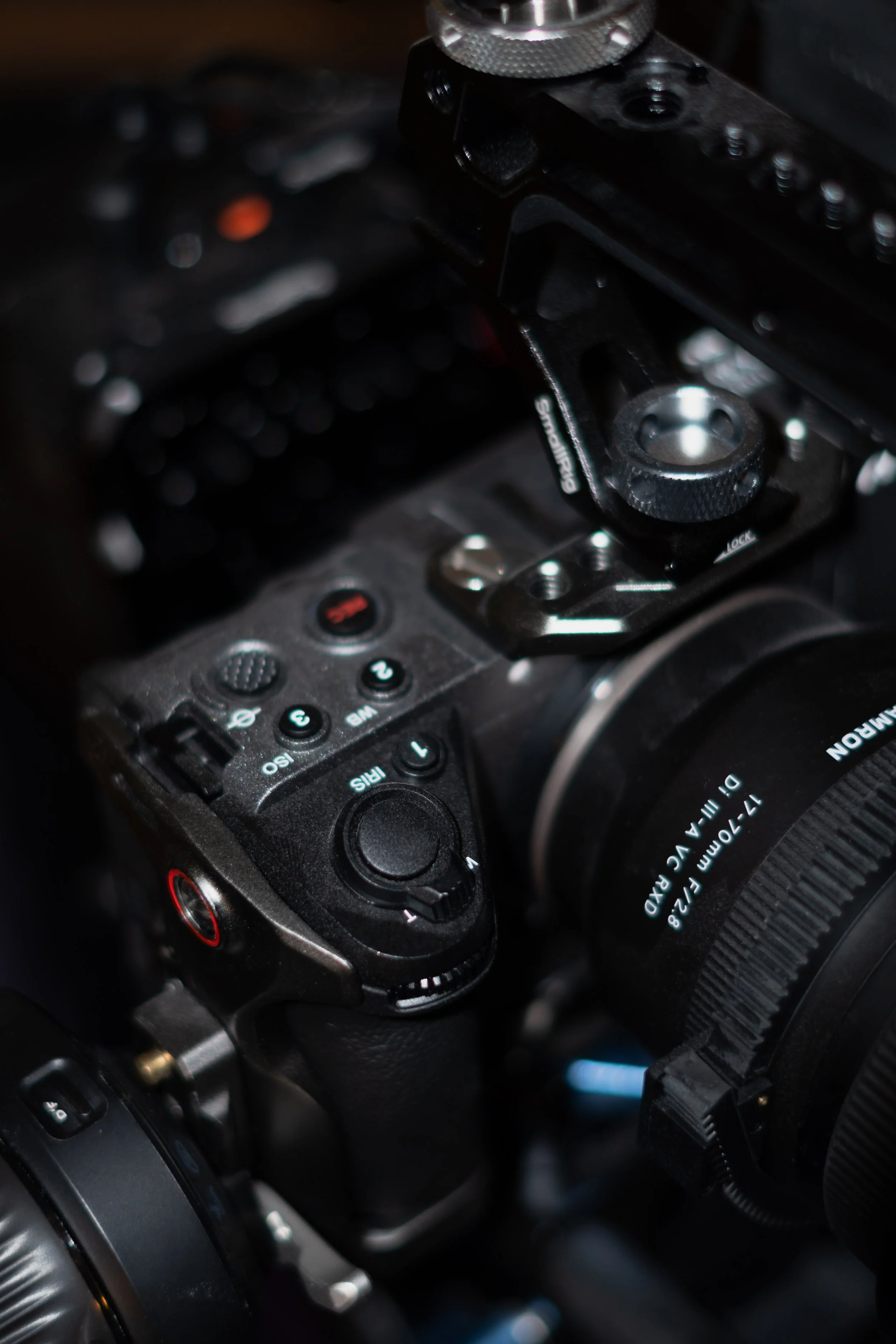Close-up of a professional camera with a large lens, focusing on the camera's mode dial and various controls.