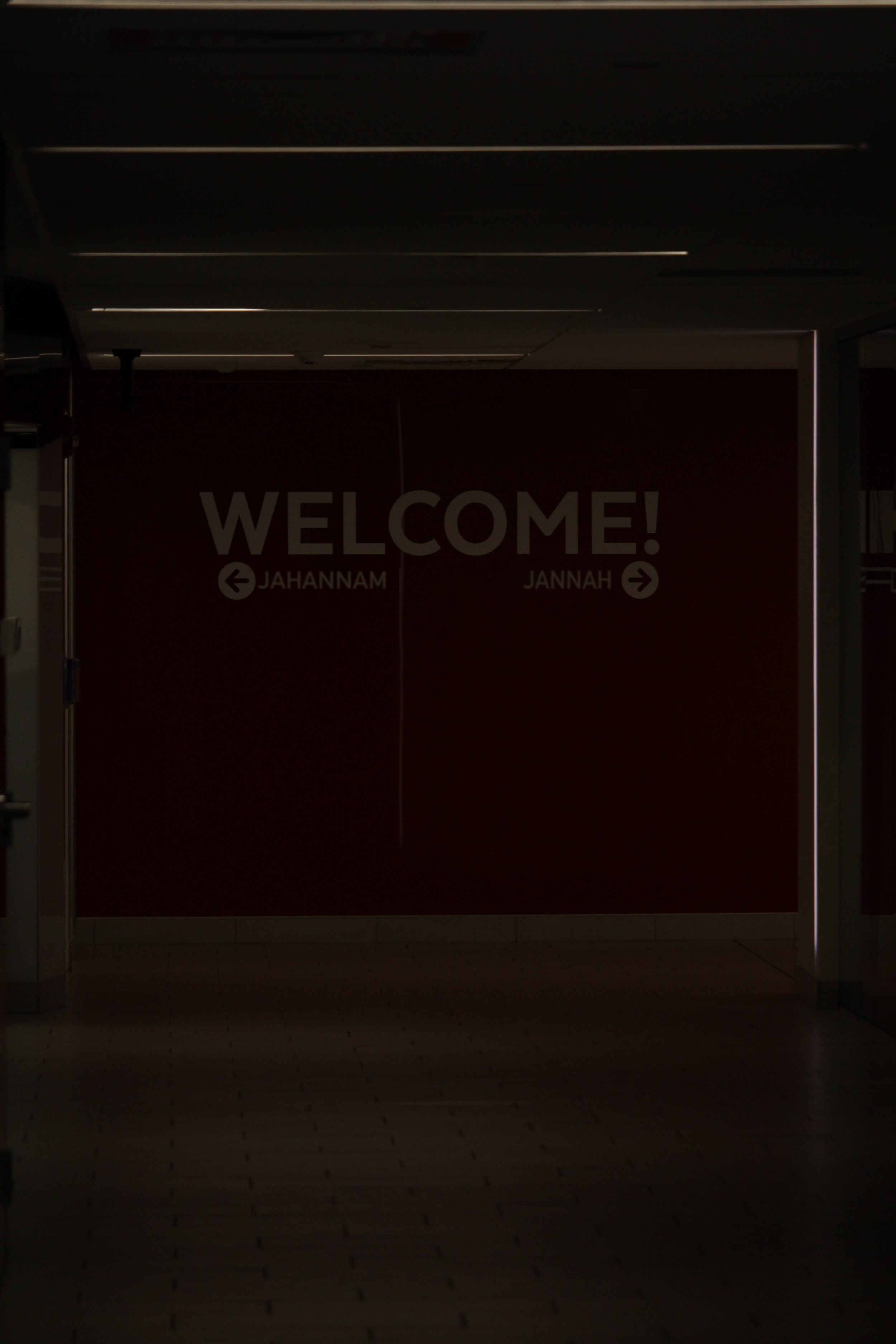 Dark interior with a large red welcome sign that says "WELCOME!" and has arrows pointing left to JAHANNAM and right to JANNAH.