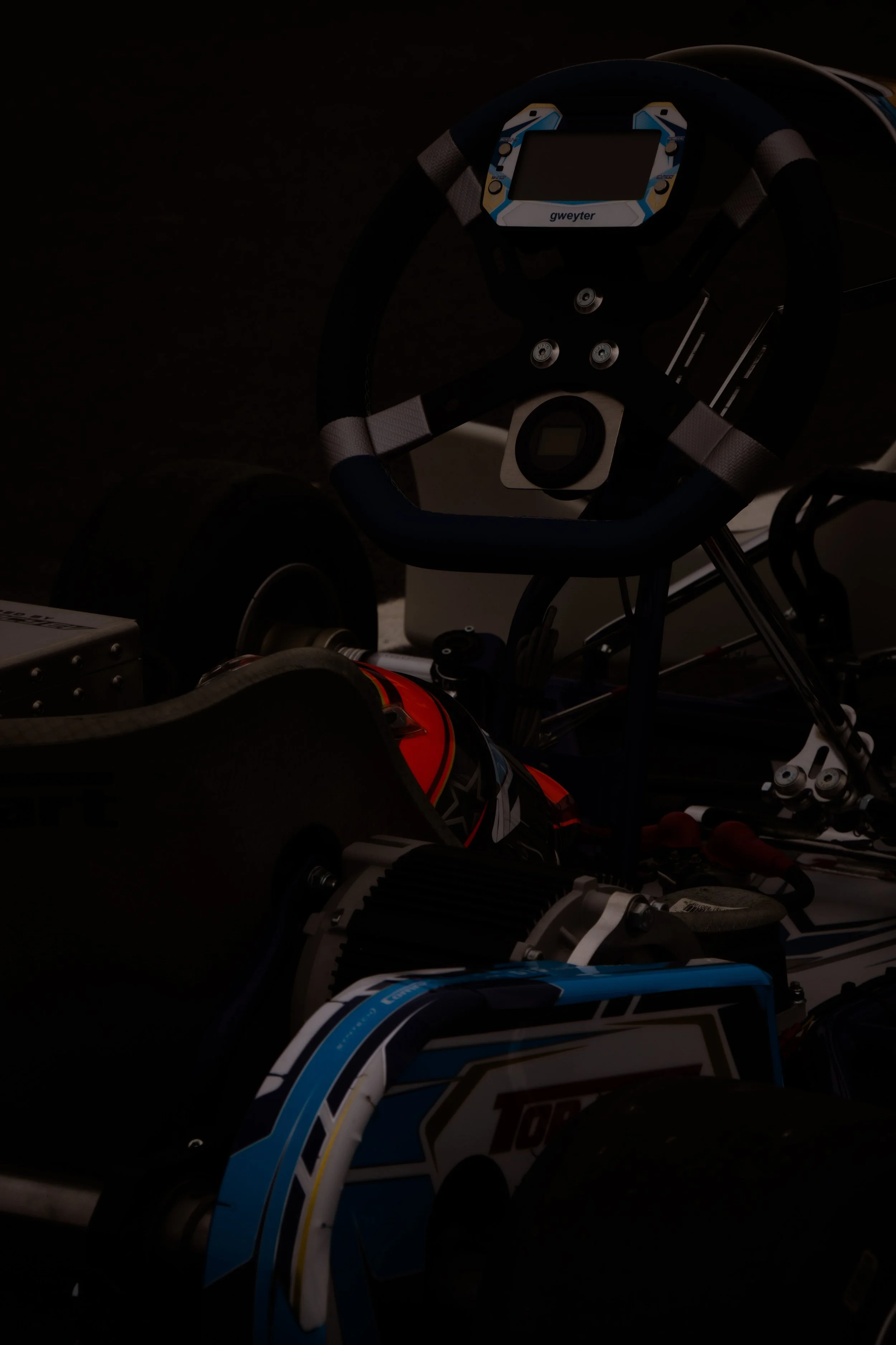 Close-up of a go-kart's steering wheel and cockpit area with visible racing helmet.