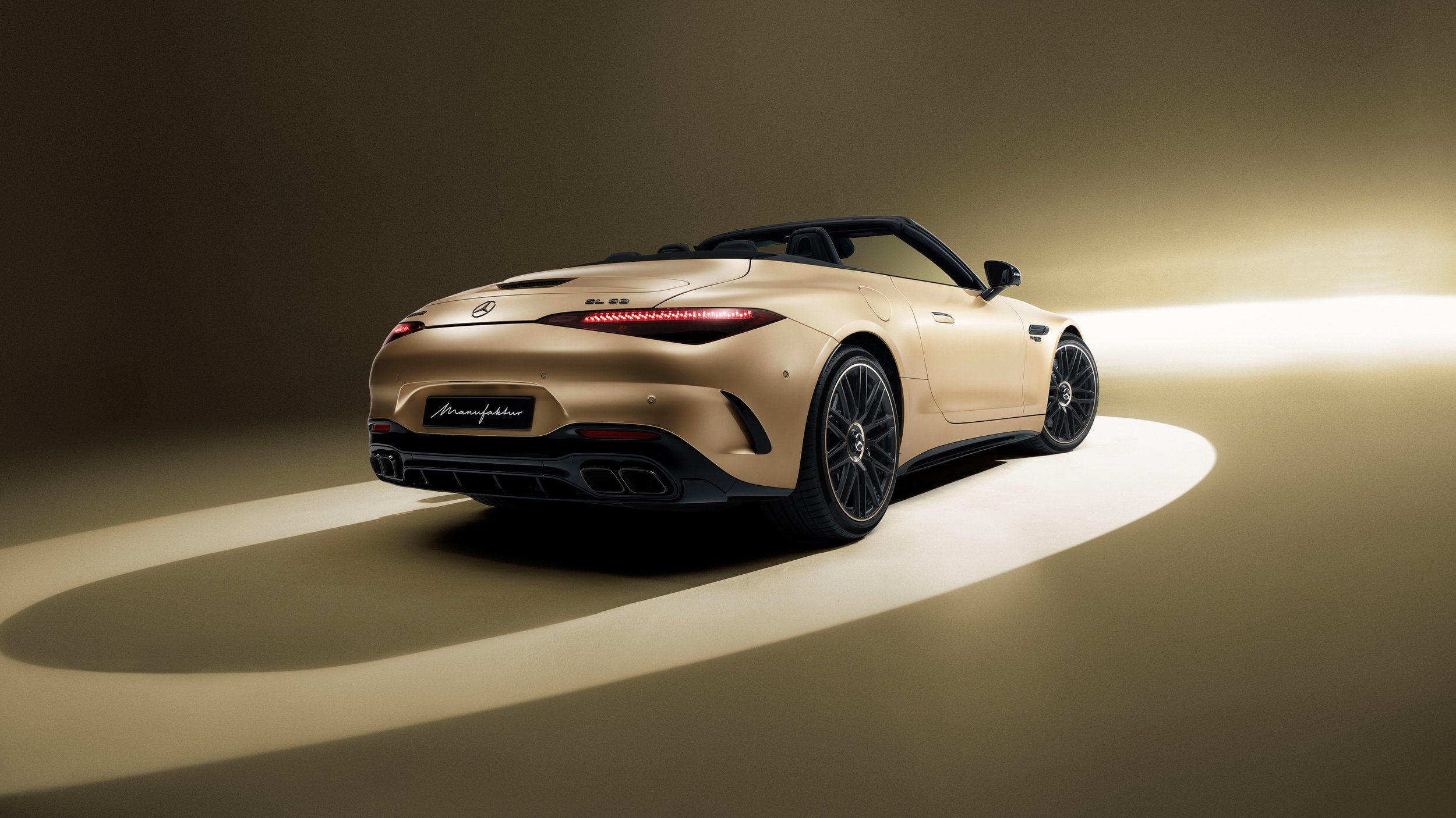 A beige Mercedes-Benz sports car with black accents, positioned on a light-colored surface against a gradient background, illuminated from the right side.