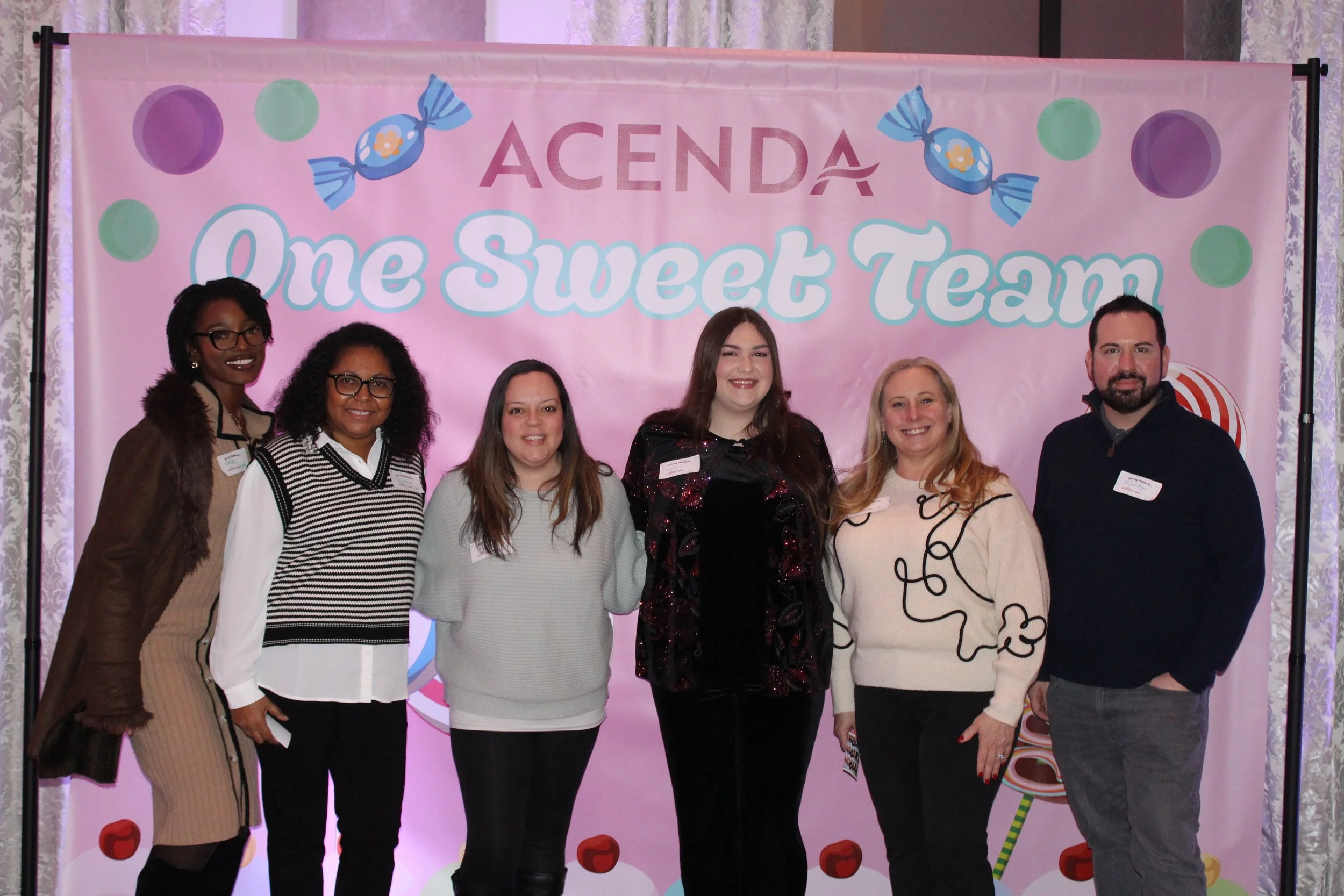 Six Acenda employees pose in front of a "One Sweet Team" backdrop for Staff Bash 2026