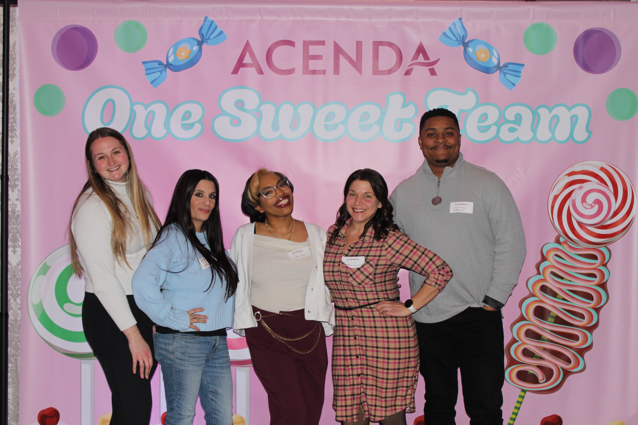 Five Acenda employees pose in front of a "One Sweet Team" backdrop for Staff Bash 2026