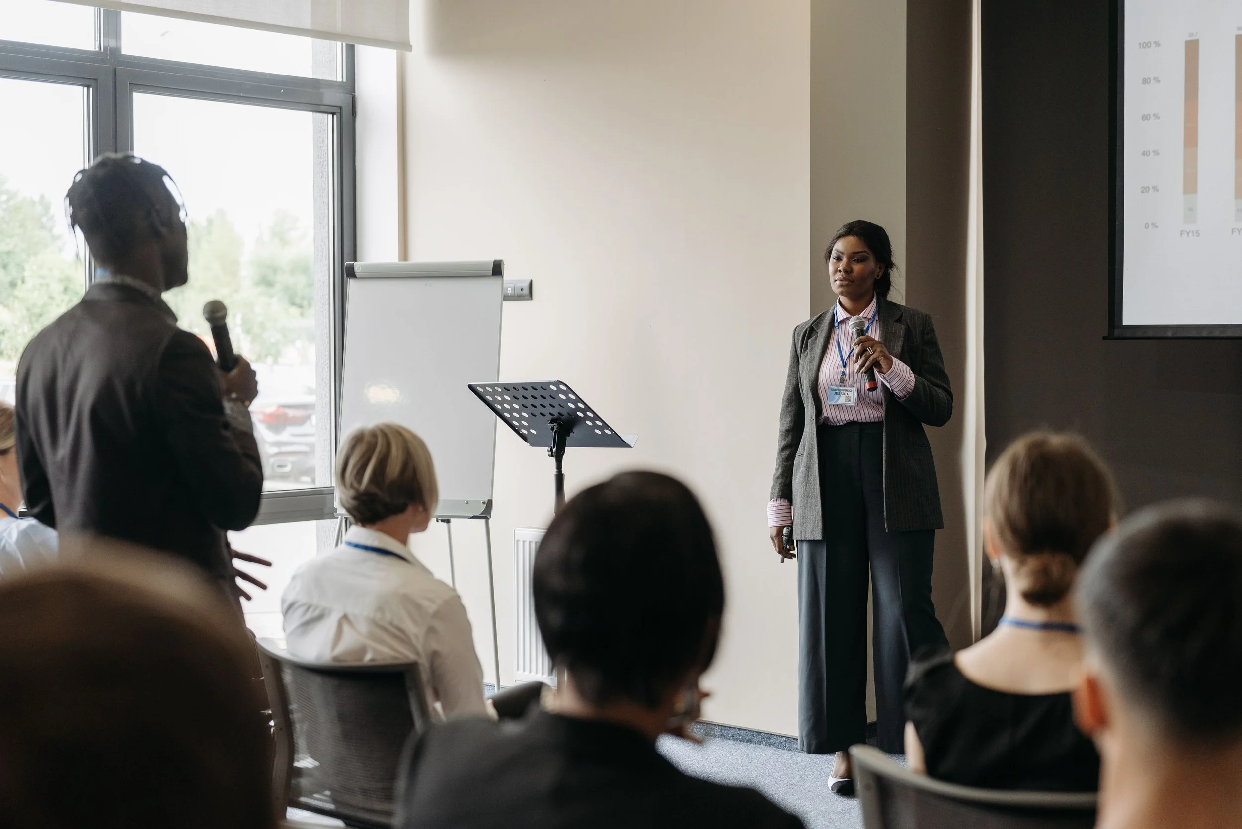 black woman presenting at a conference and answering question from audience member