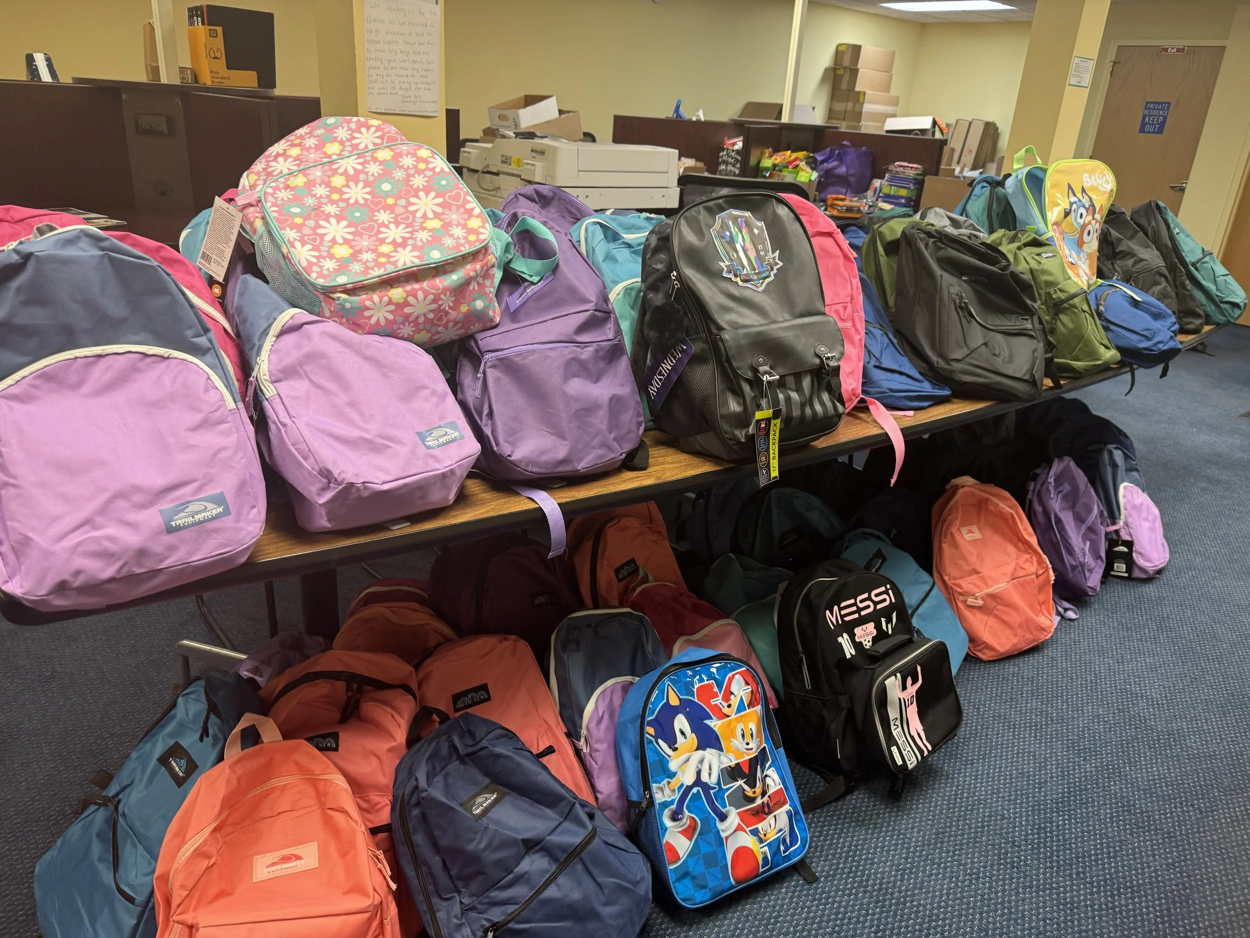 New backpacks stacked on tables for Acenda's annual backpack drive