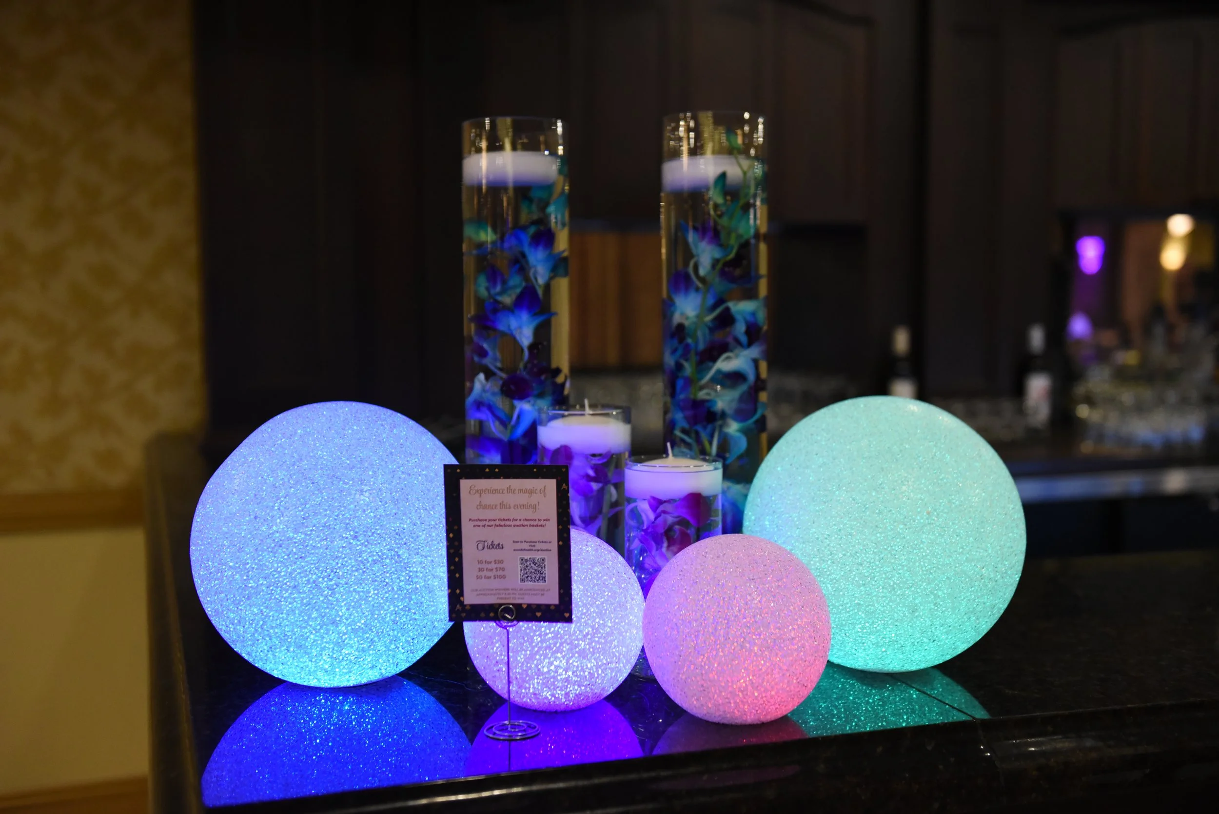 2025 Vegas Mystique decor featuring blue, purple, pink, and green light-up sparkly balls and flowers